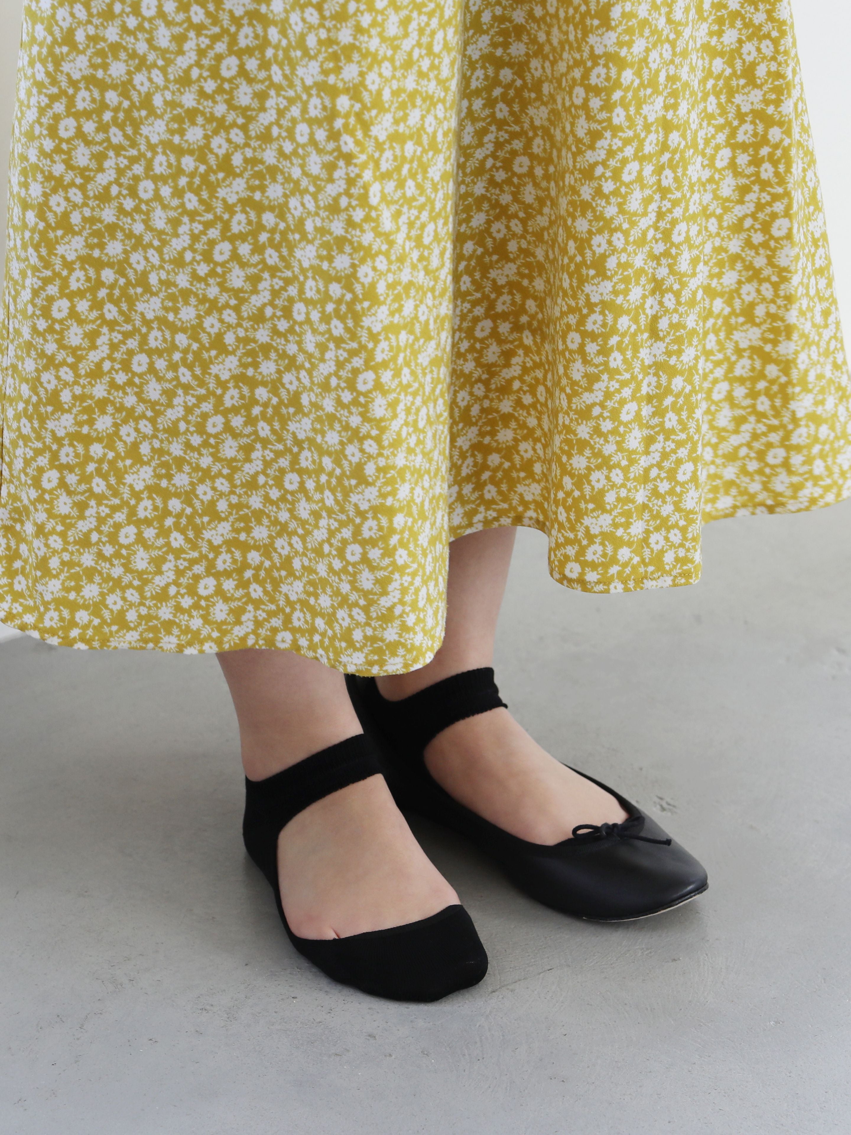 Tabio Sandal Type Sockette showcased in black, featuring an ankle strap design, worn with a floral skirt.