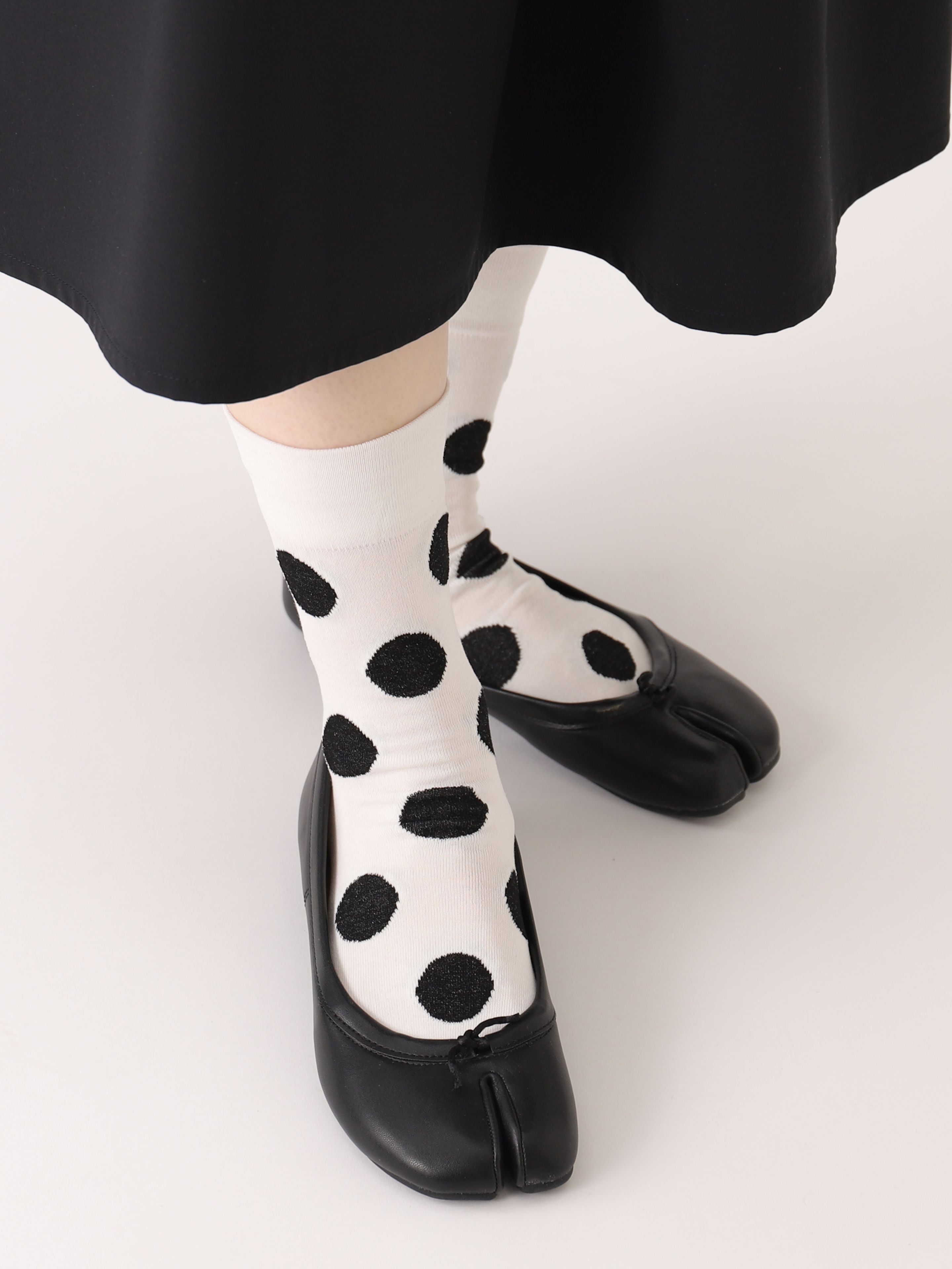 Tabio Big Dots Tabi Socks showcased on-model, featuring bold black dots against a cream background, paired with black shoes.