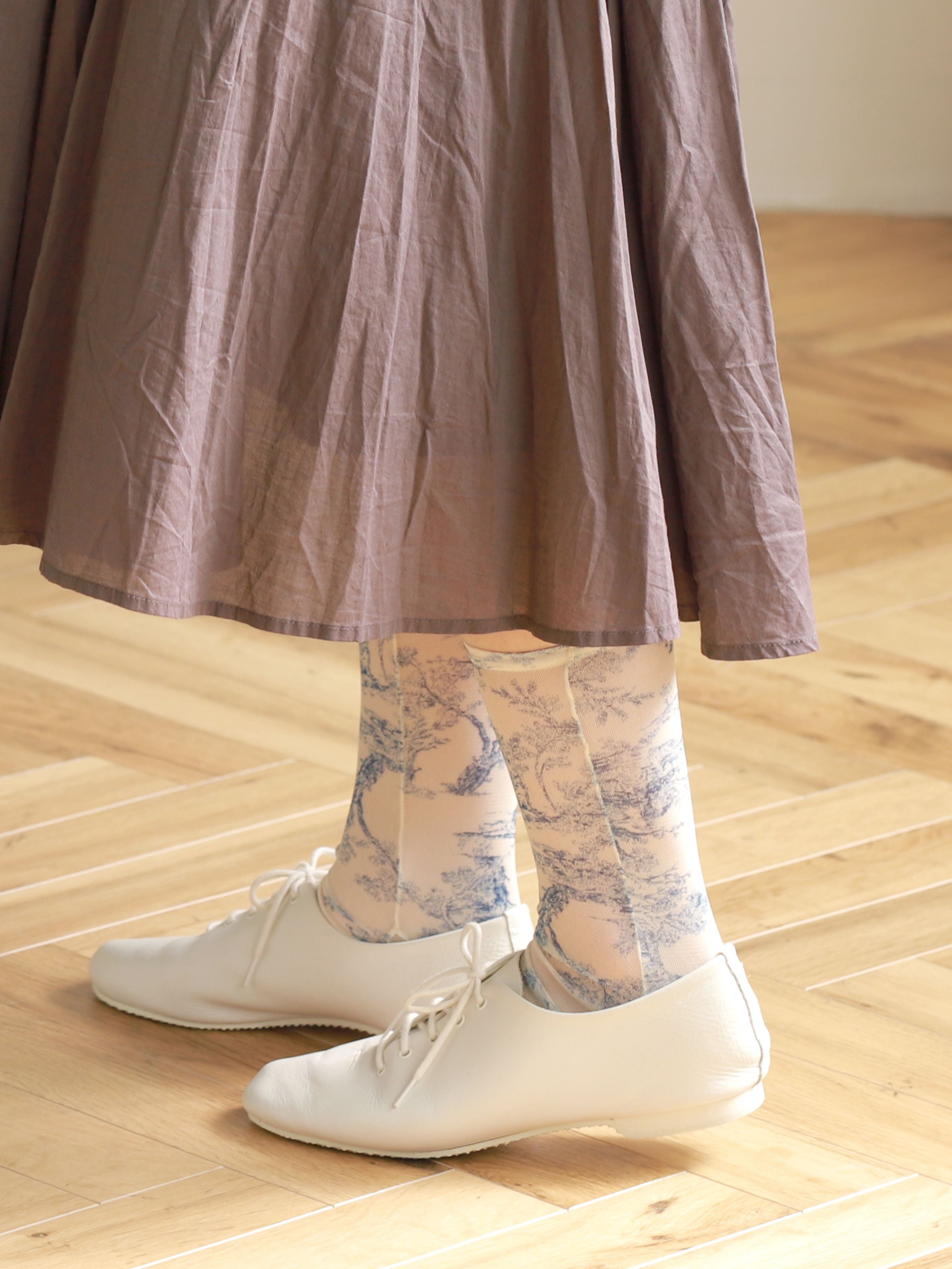 Tabio. Sheer Toile De Jouy Crew Socks displayed on model, featuring an elegant toile de Jouy print in blue tones.