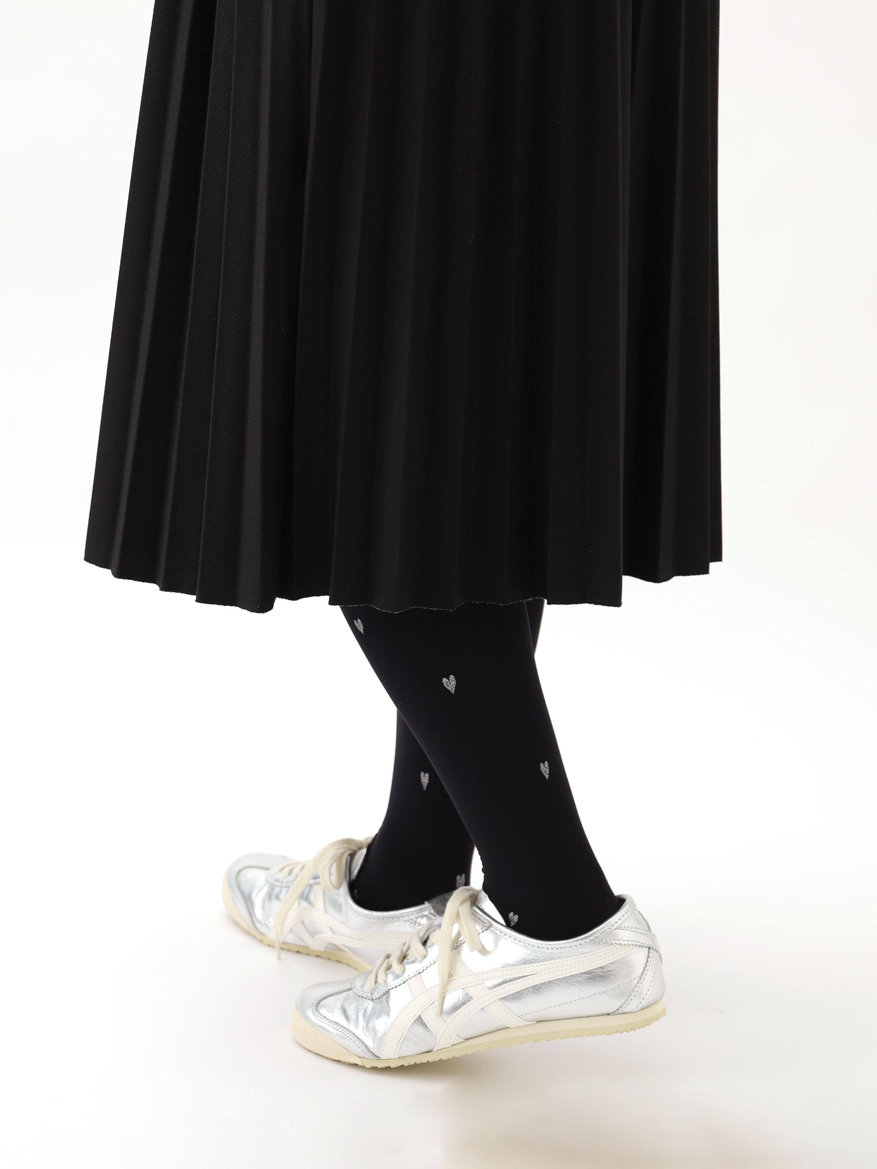 Tabio. Heart Pattern Lamé 60D Tights showcased with a pleated skirt and silver sneakers, highlighting the delicate heart.