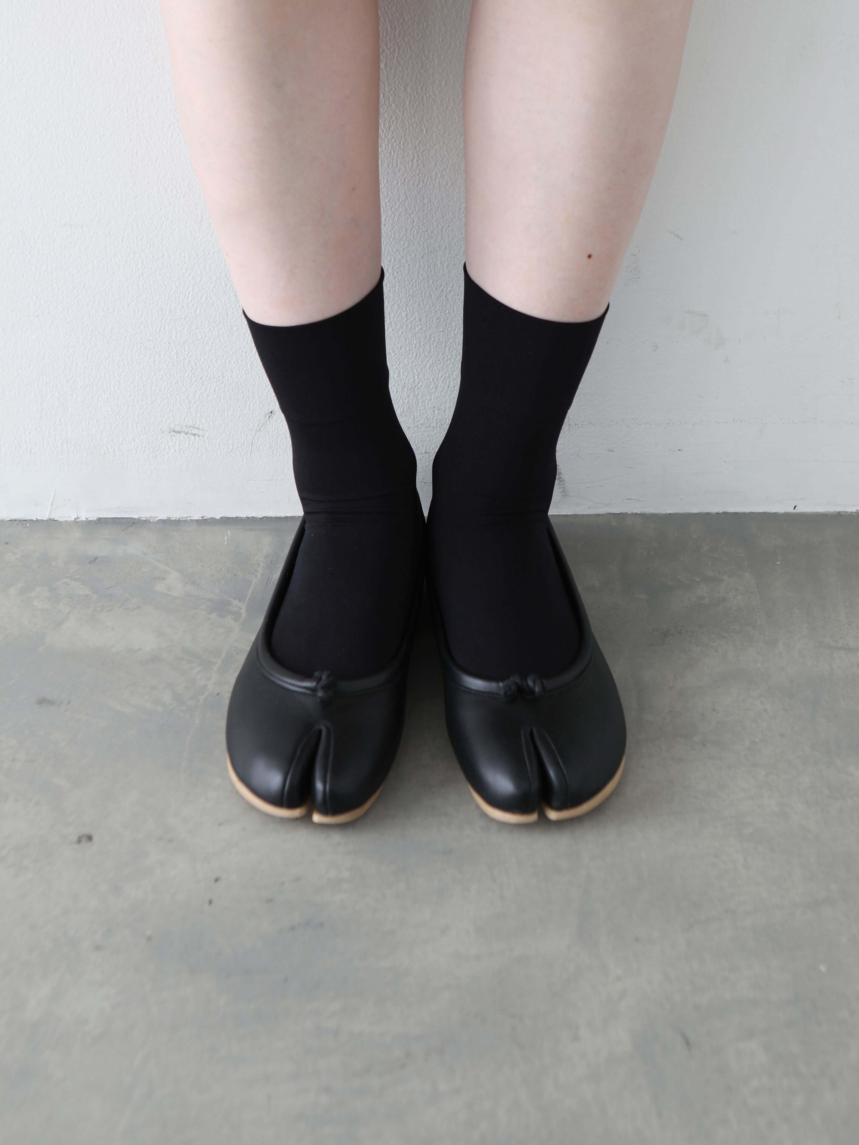 Tabio Soft Nylon Low Crew Tabi Socks in black, worn with tabi shoes, showcasing soft, stretchy material and unique design.