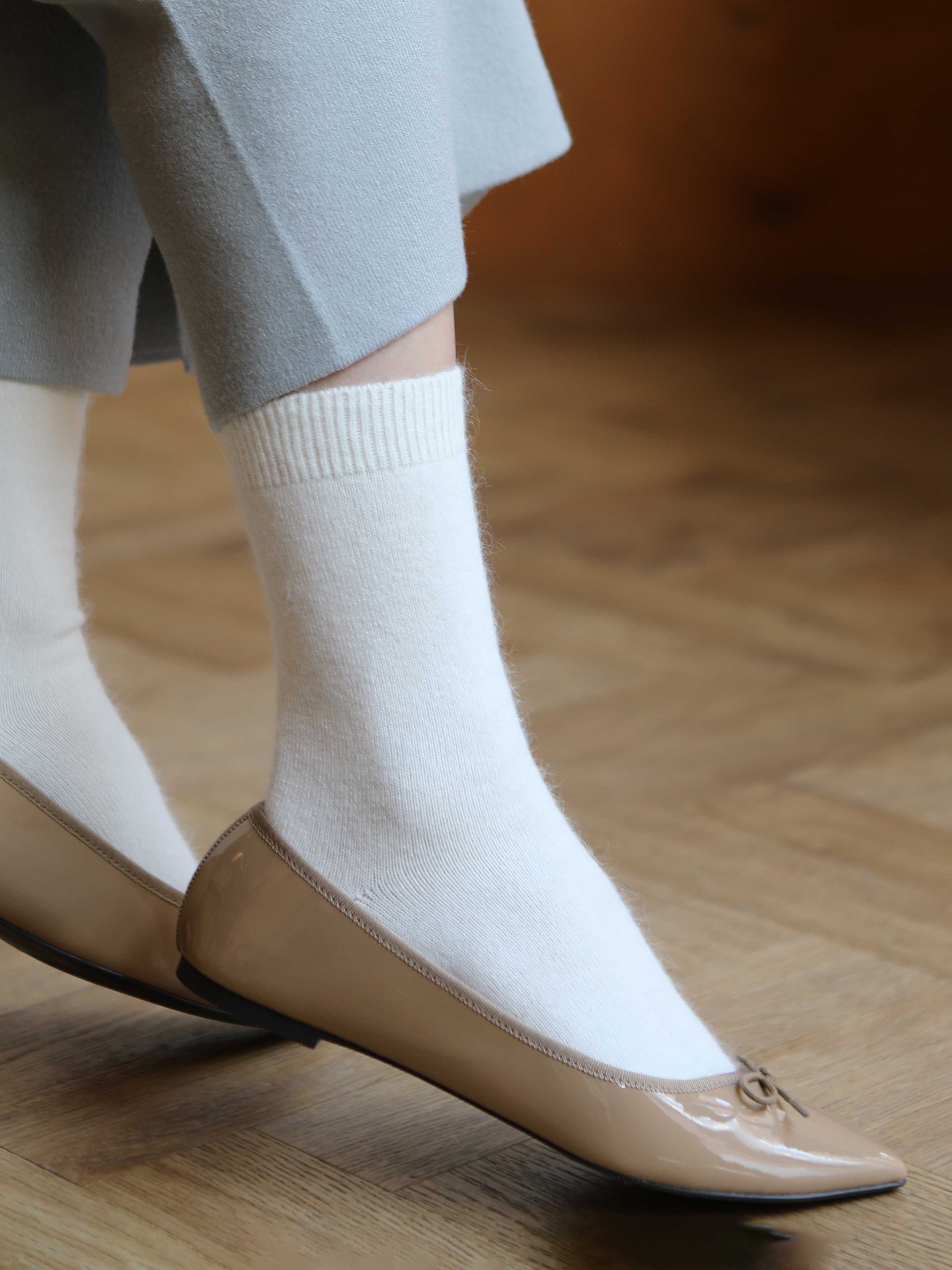 Tabio Soft Fit Angora Plain Sock in white, featuring a cozy ribbed cuff, elegantly paired with beige flats.