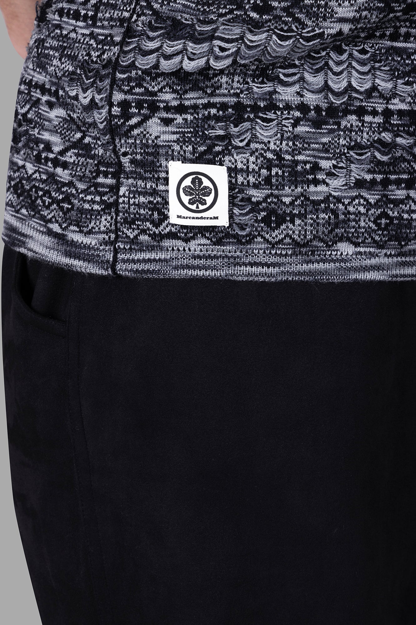 Marc Point Melange Sweater Vest detail shot showing textured black and grey wool fabric with brand label on side.