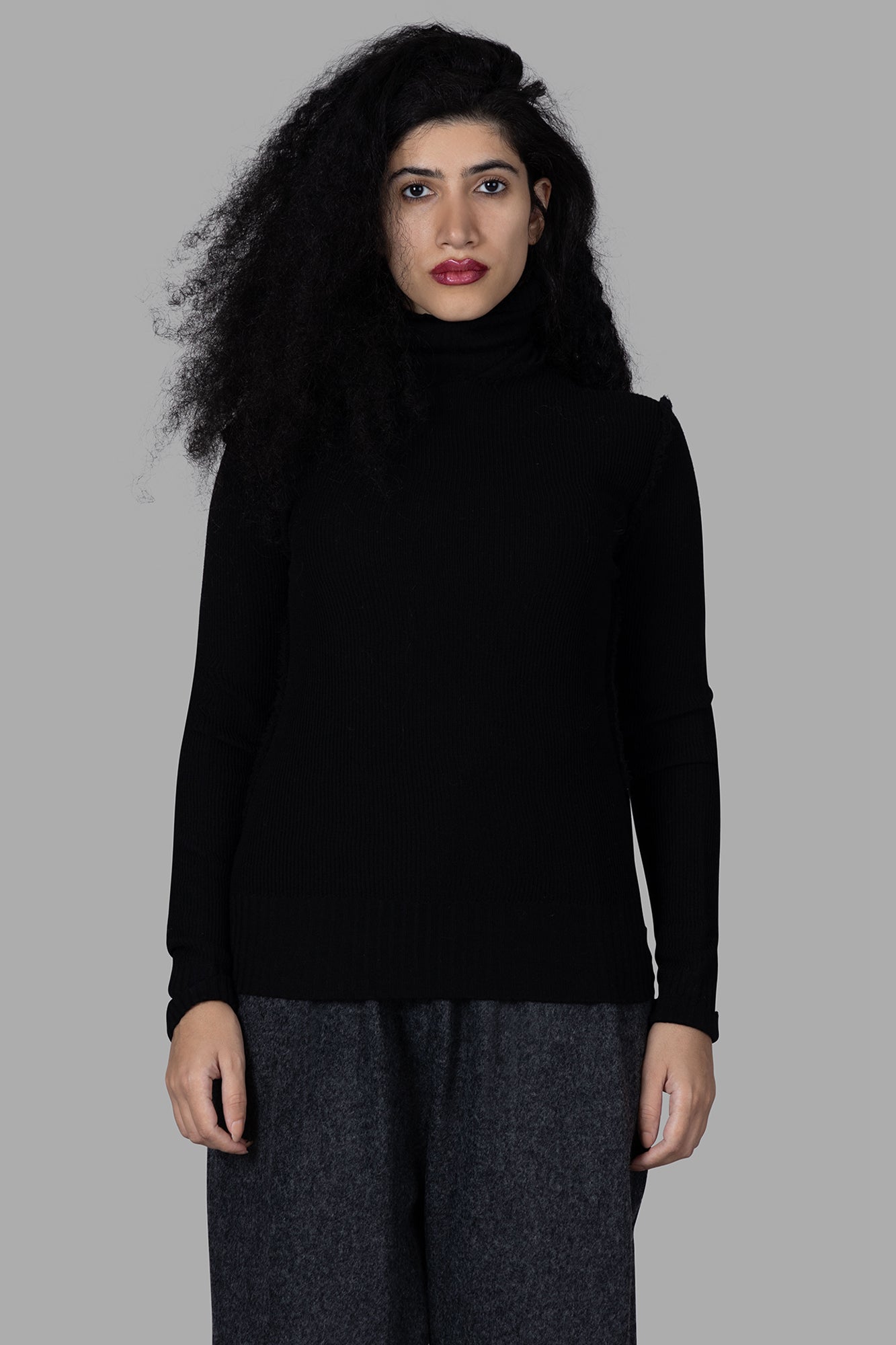 Marc Point Roll-neck Sweater in black, featuring a cozy ribbed texture, elegantly styled on a model against a gray.