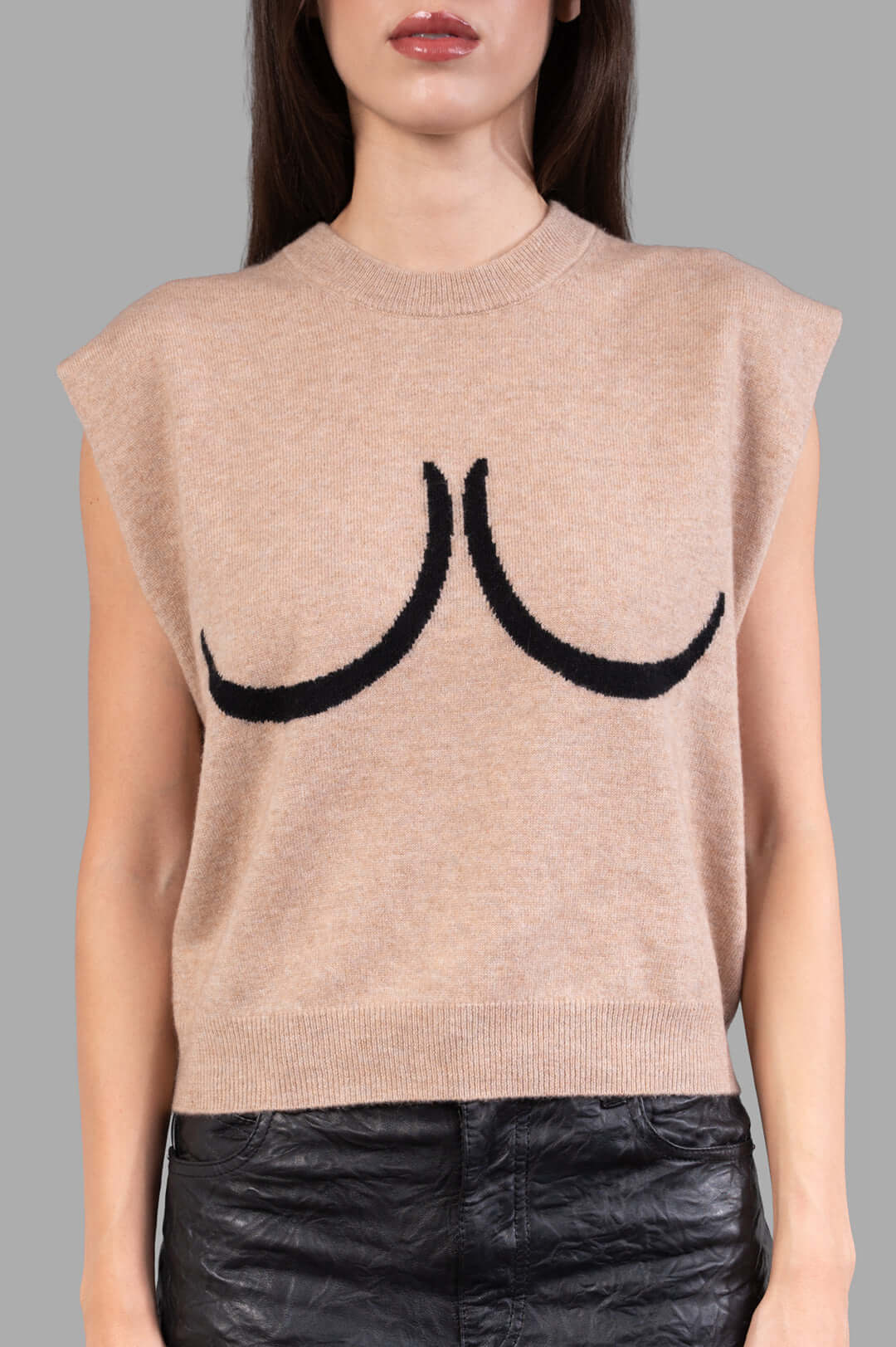 **Alt Text:** Natasha Zinko Breast Sweater Vest shown on model, featuring bold black breast motif and soft beige fabric.