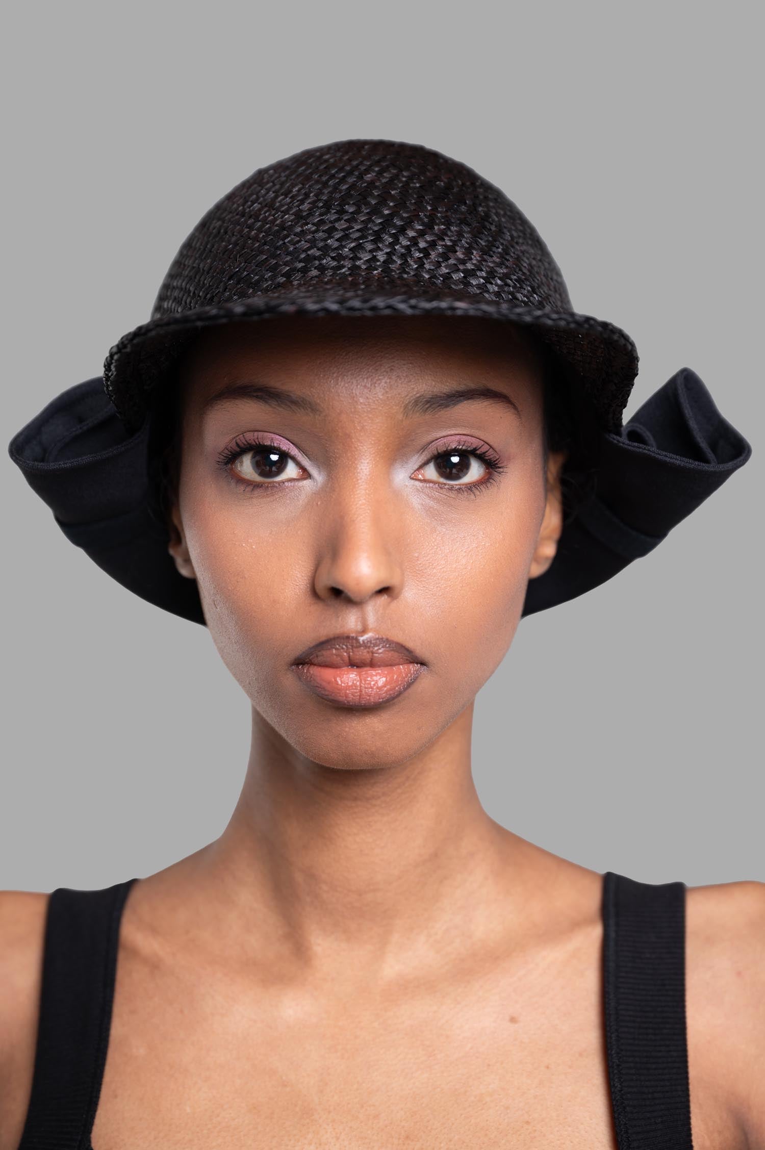 Kijima Takayuki Straw Sun Hat in black, featuring unique bow detail and crafted from 100% raffia. Front model view.