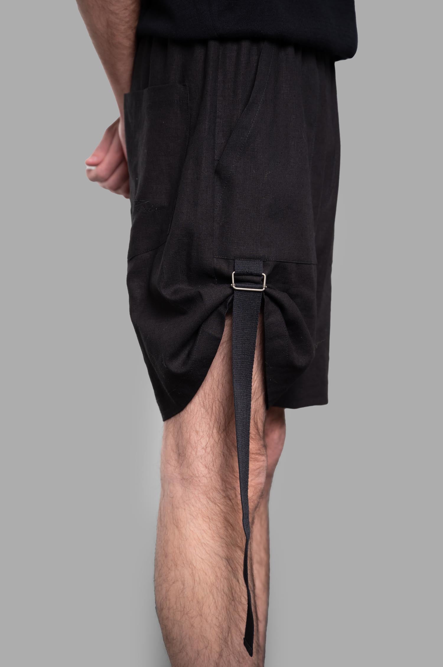 Gaëlle Paris Bermuda Shorts displayed from the side, featuring a unique adjustable strap detail and practical side pocket.
