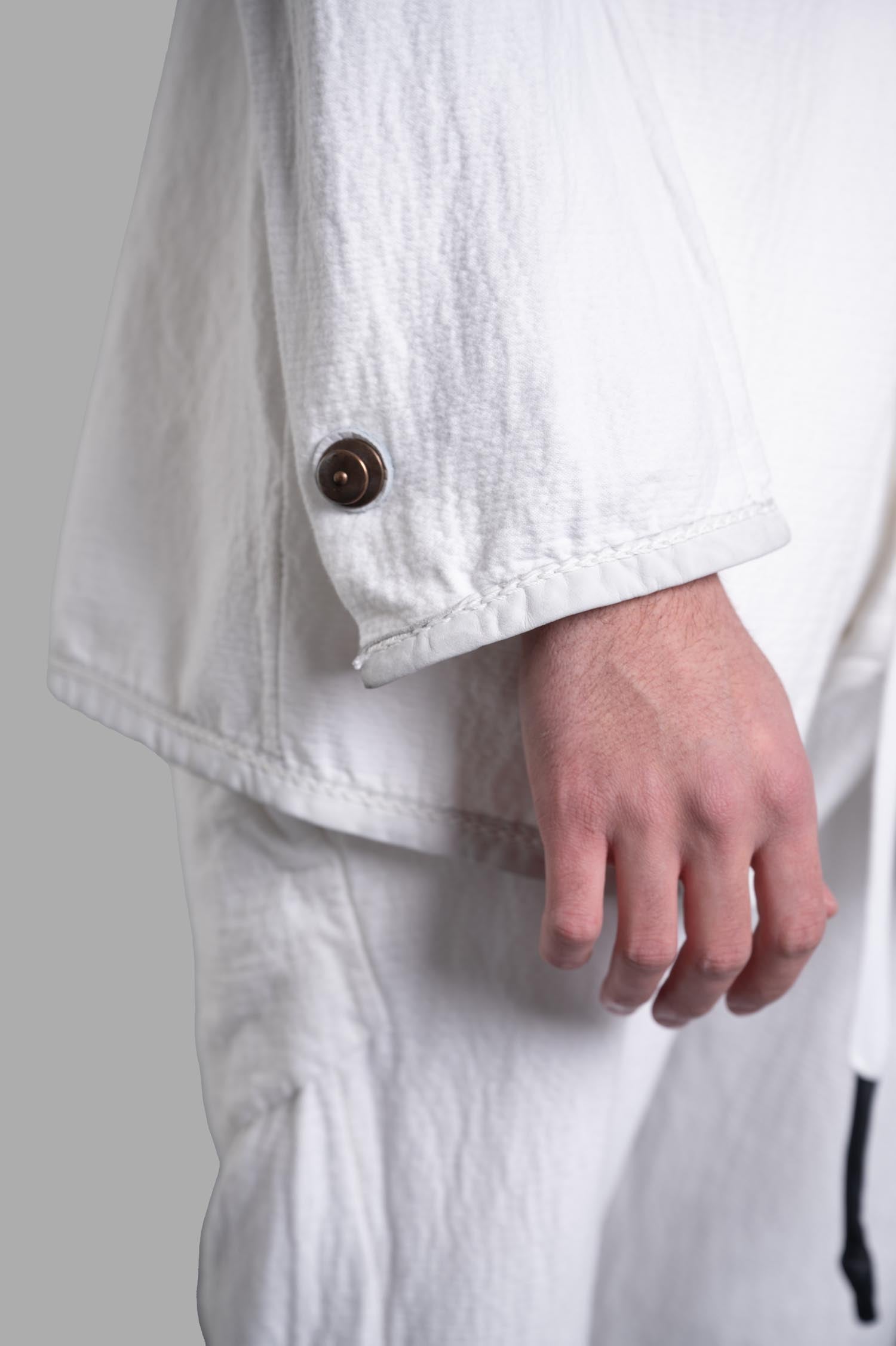 Isaac Sellam Crinkled Blazer close-up detailing leather piping and buttons on the sleeve in organic cotton, white color.