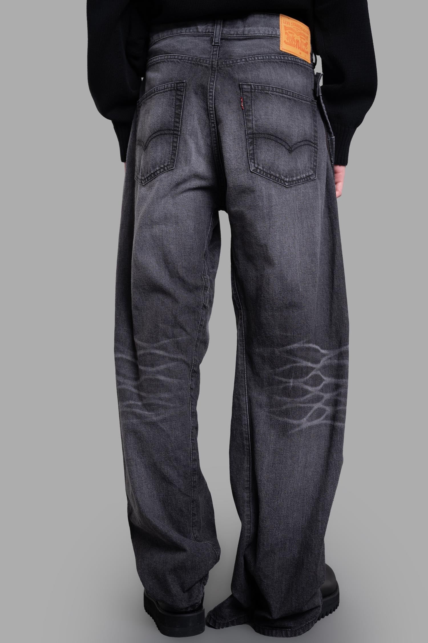 Junya Watanabe x Levi's® Wraparound Jeans, showcasing a unique grey back view with applied logo and distress detail.