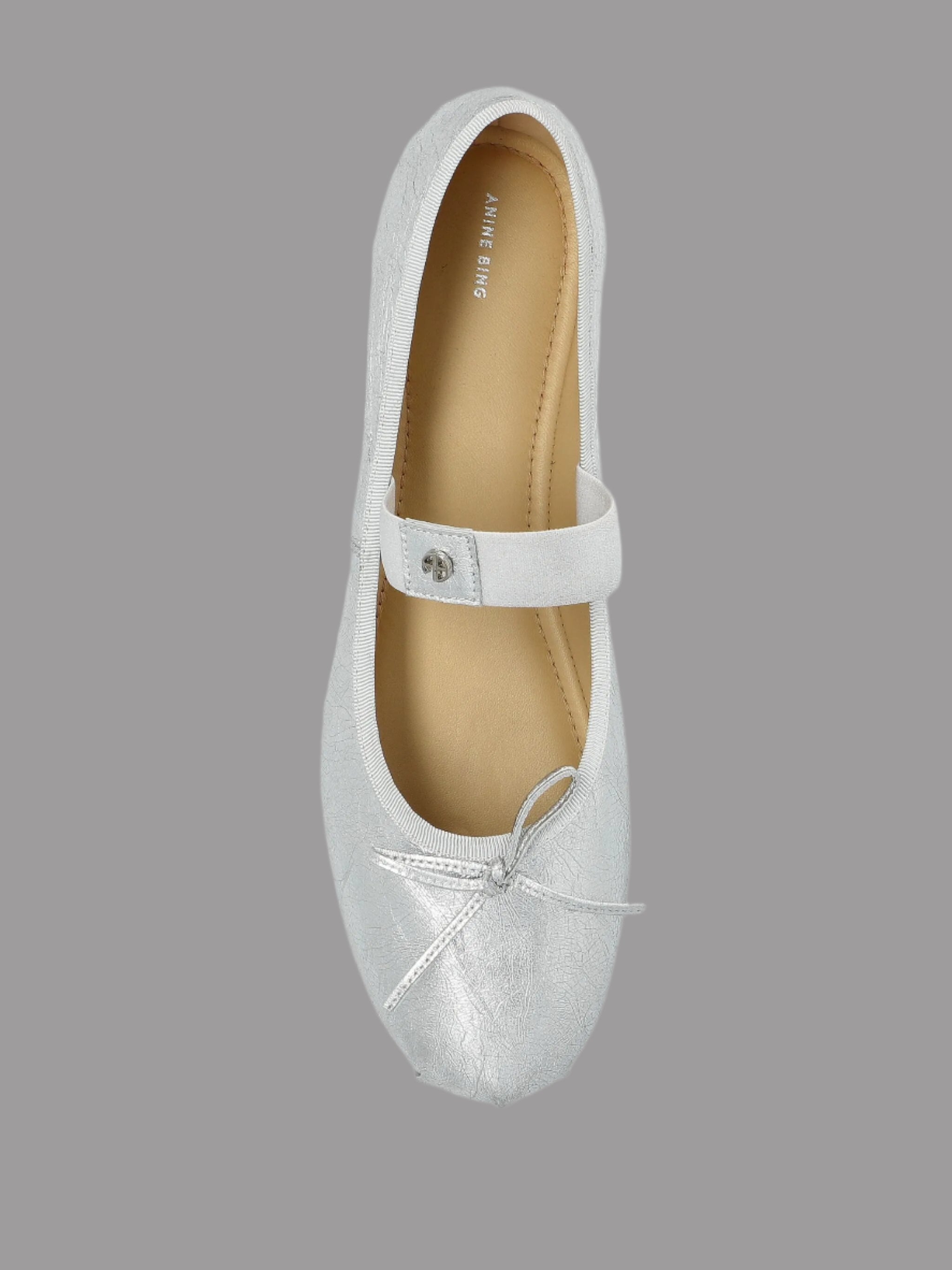 Anine Bing Jolie Flats in silver, featuring a rounded toe, leather bow, elastic strap, and flexible outsole. Top view.