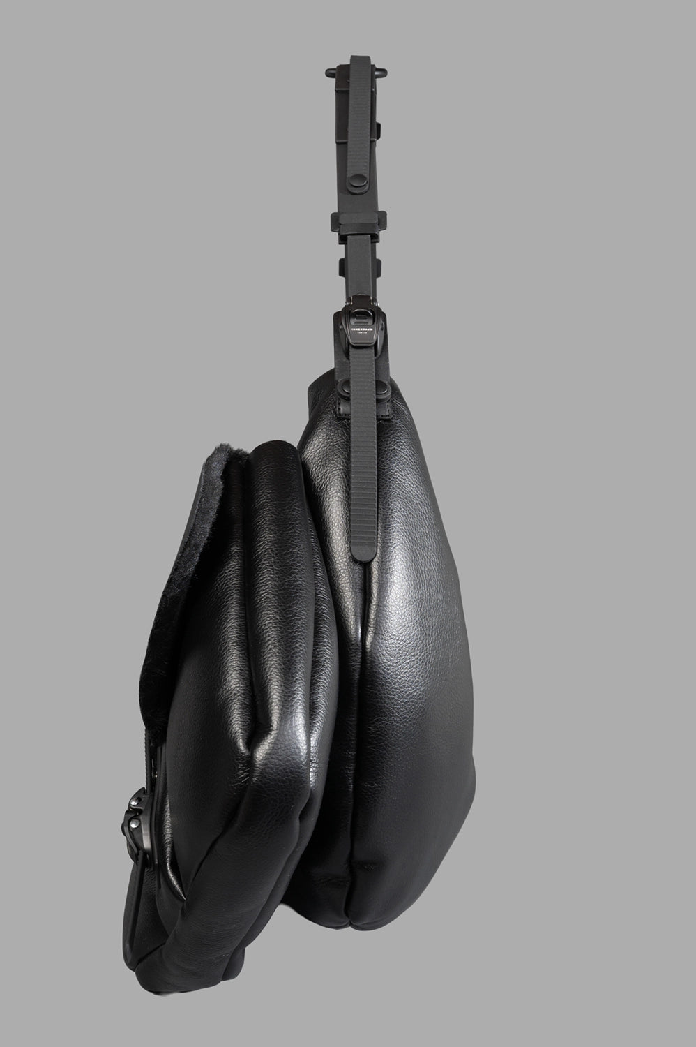 Innerraum Half Moon Bag with Pockets displayed from the side, showcasing its matte black texture and adjustable strap.