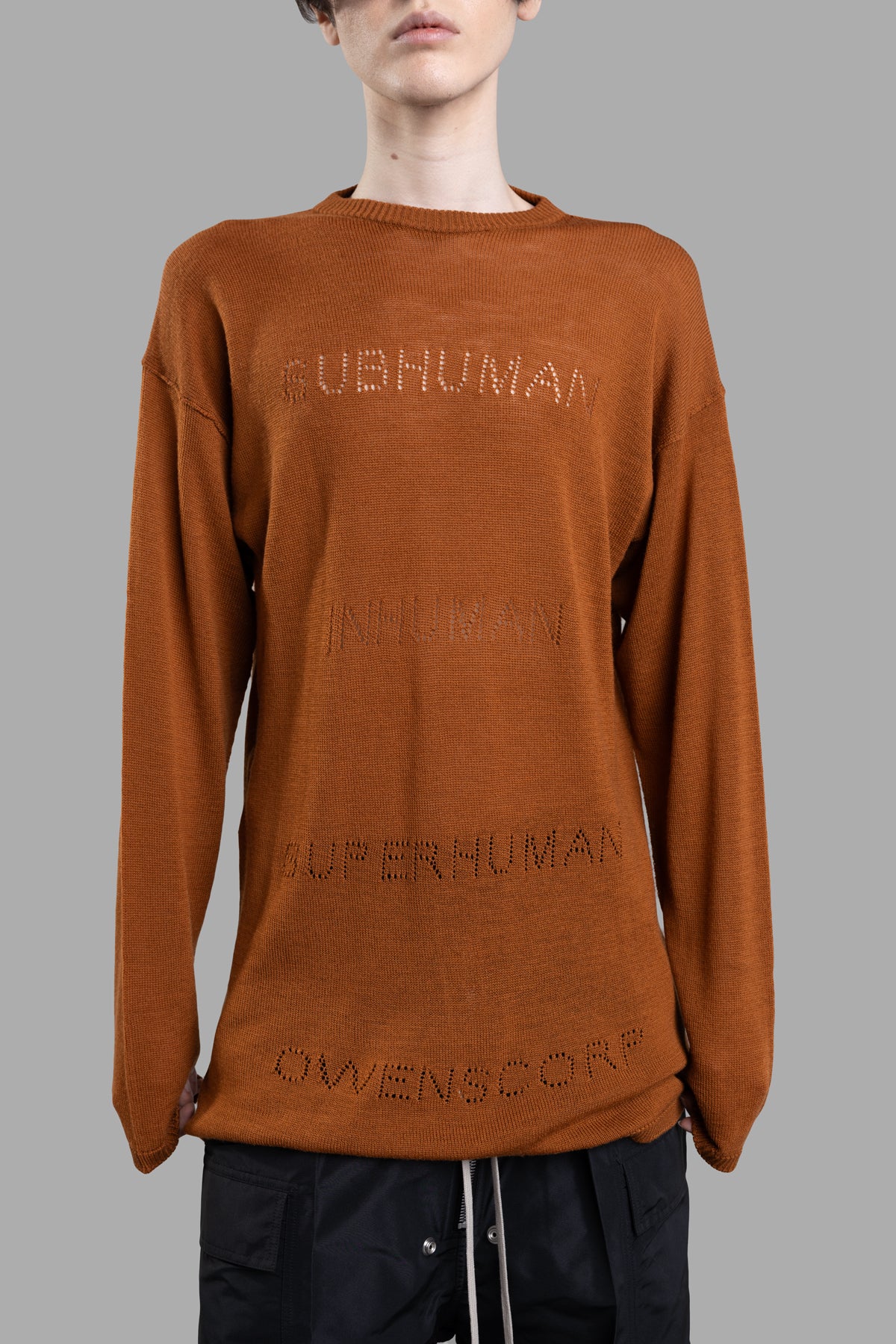 Rick Owens Oversized Sweater features a loose fit, wide shoulders, and jacquard lettering in a clay hue, styled on a model.