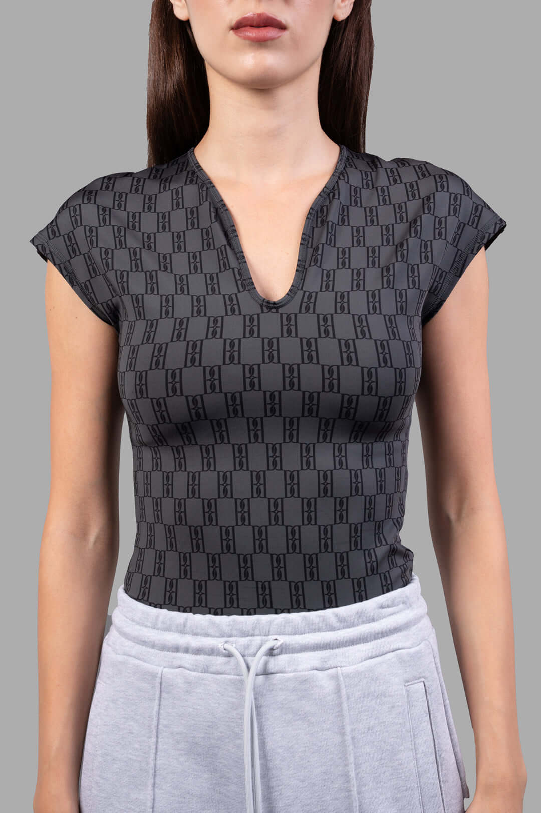 By Malene Birger Venazia Athletic Top in black & grey, featuring a V-neck and body-hugging fit, shown on model.