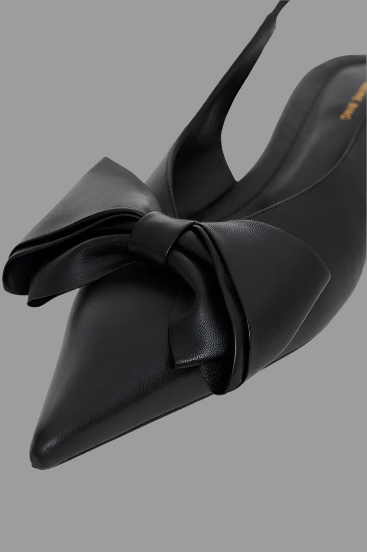 Anine Bing. Close-up of Nina Slingback Bow Flats in black leather featuring oversized bow and pointed toe design.