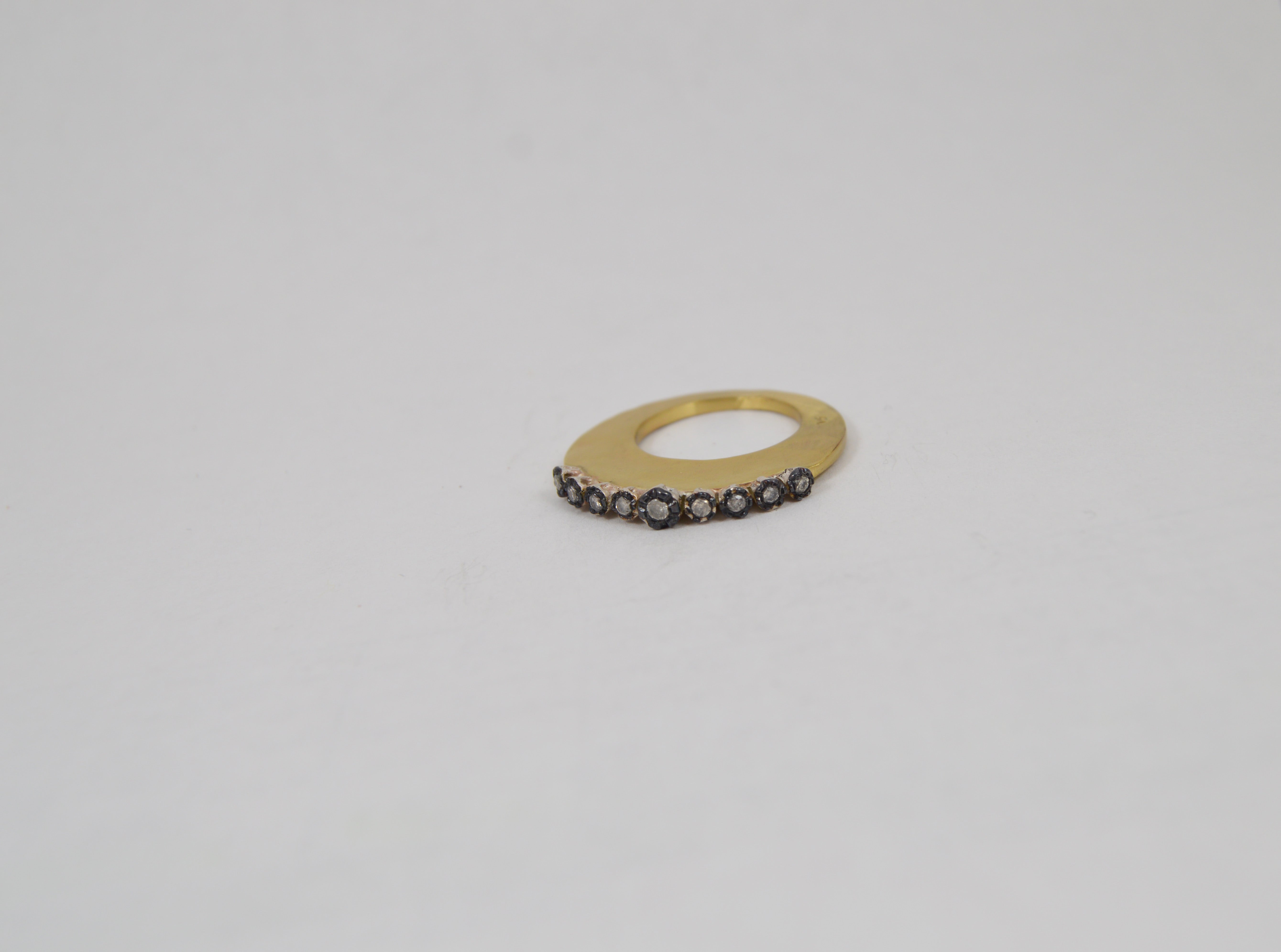 Rosa Maria Brennon Ring shown from side, featuring a sleek gold band adorned with small, dark gemstones.