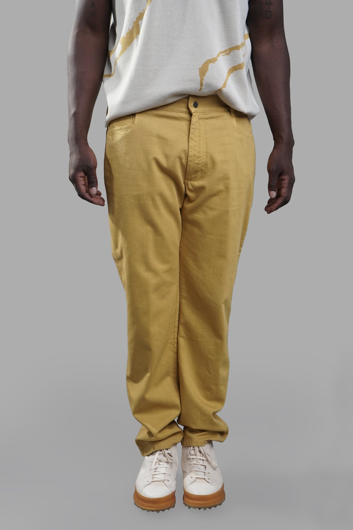 AION. Ochre Jeans displayed on a model, featuring a relaxed fit in yellow, perfect for versatile styling and comfort.