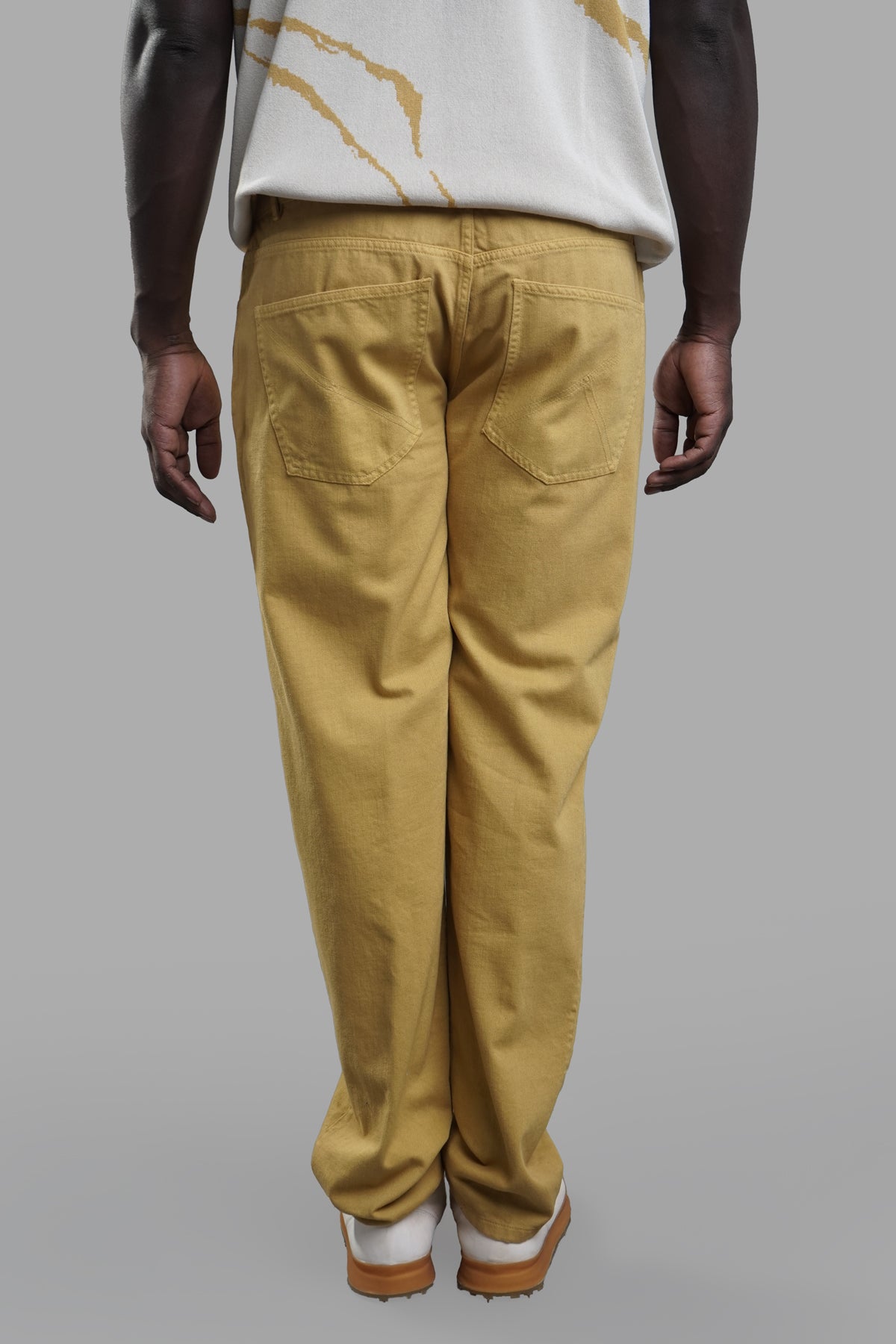 AION. Ochre Jeans in yellow showcased from the back, featuring a relaxed fit and classic 5-pocket design.
