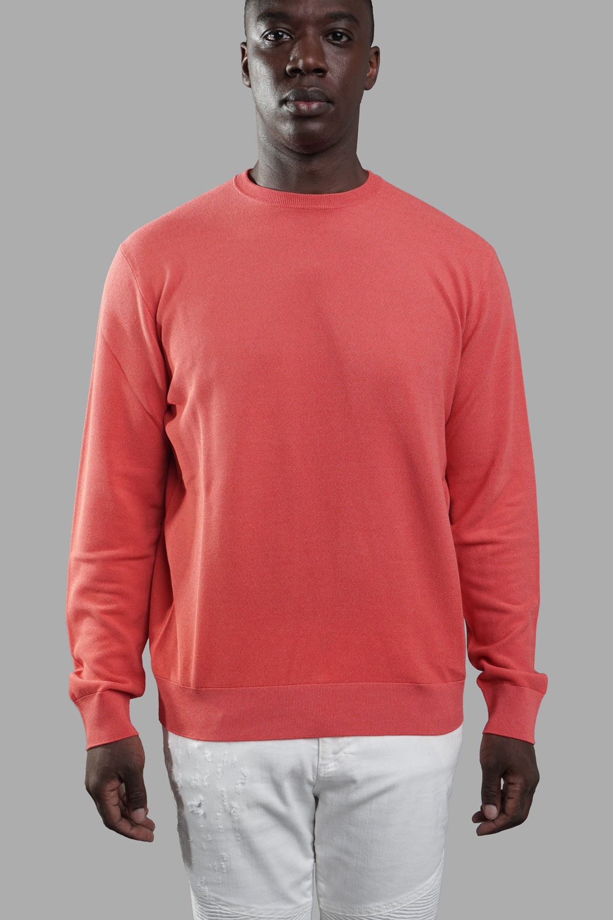 AION. Coral Sweater in soft coral shade, relaxed-fit design with round neck and ribbed cuffs showcased on model.