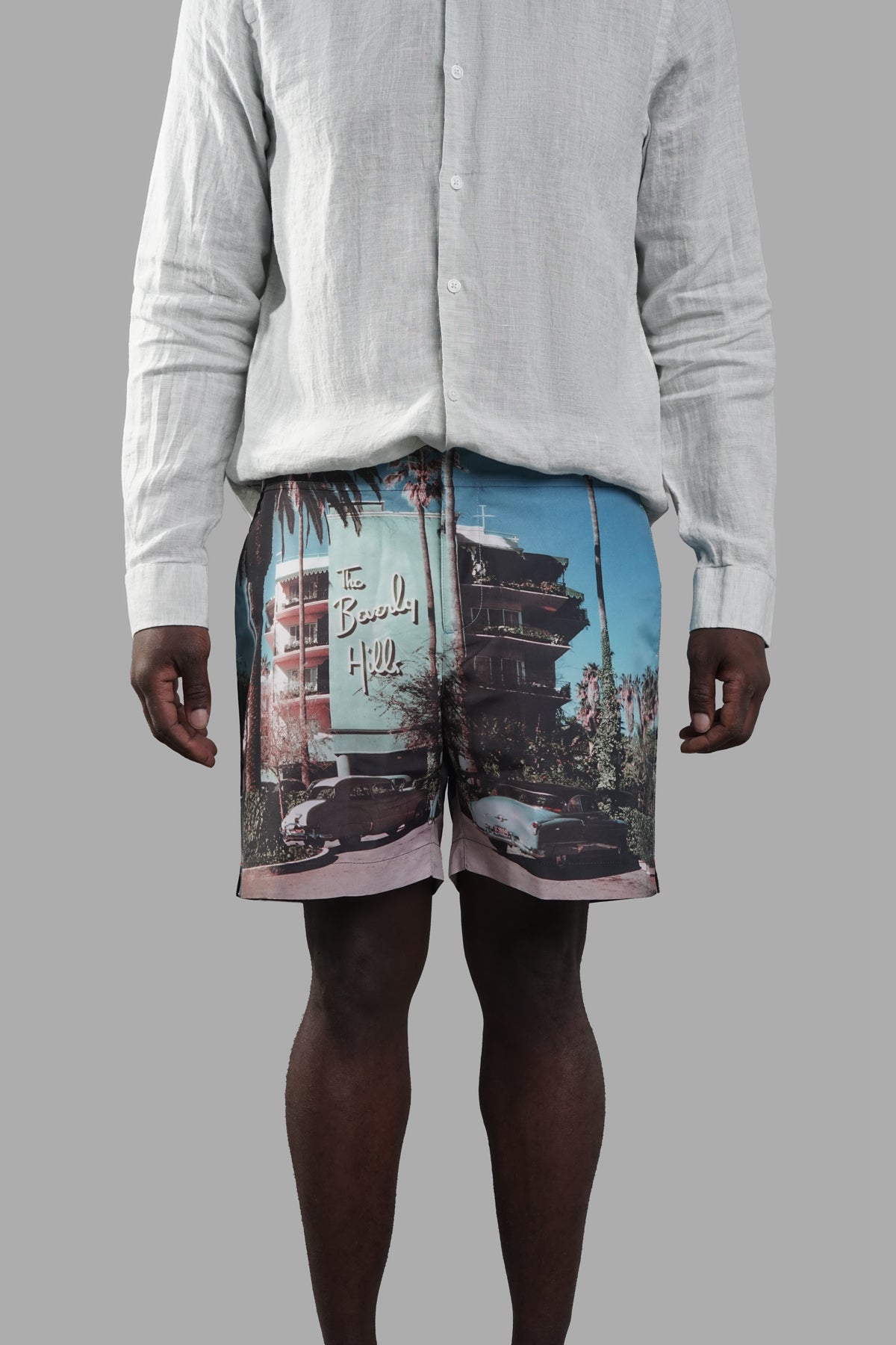 Orlebar Brown Beverly Hills Swim Shorts displayed on a model, featuring front print of palm trees and classic cars.