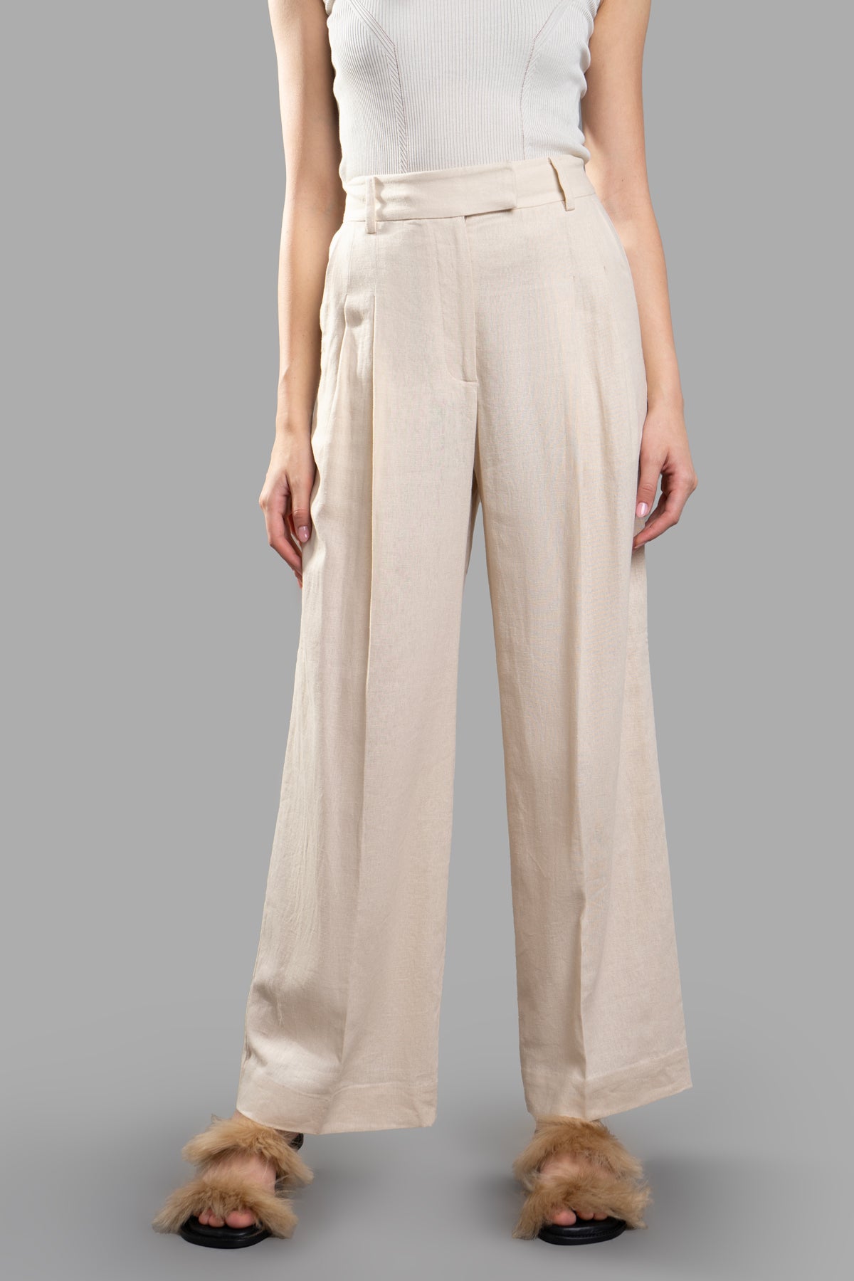 By Malene Birger High-waisted Trousers shown from the front, featuring flared wide legs and pressed pleats in beige linen.
