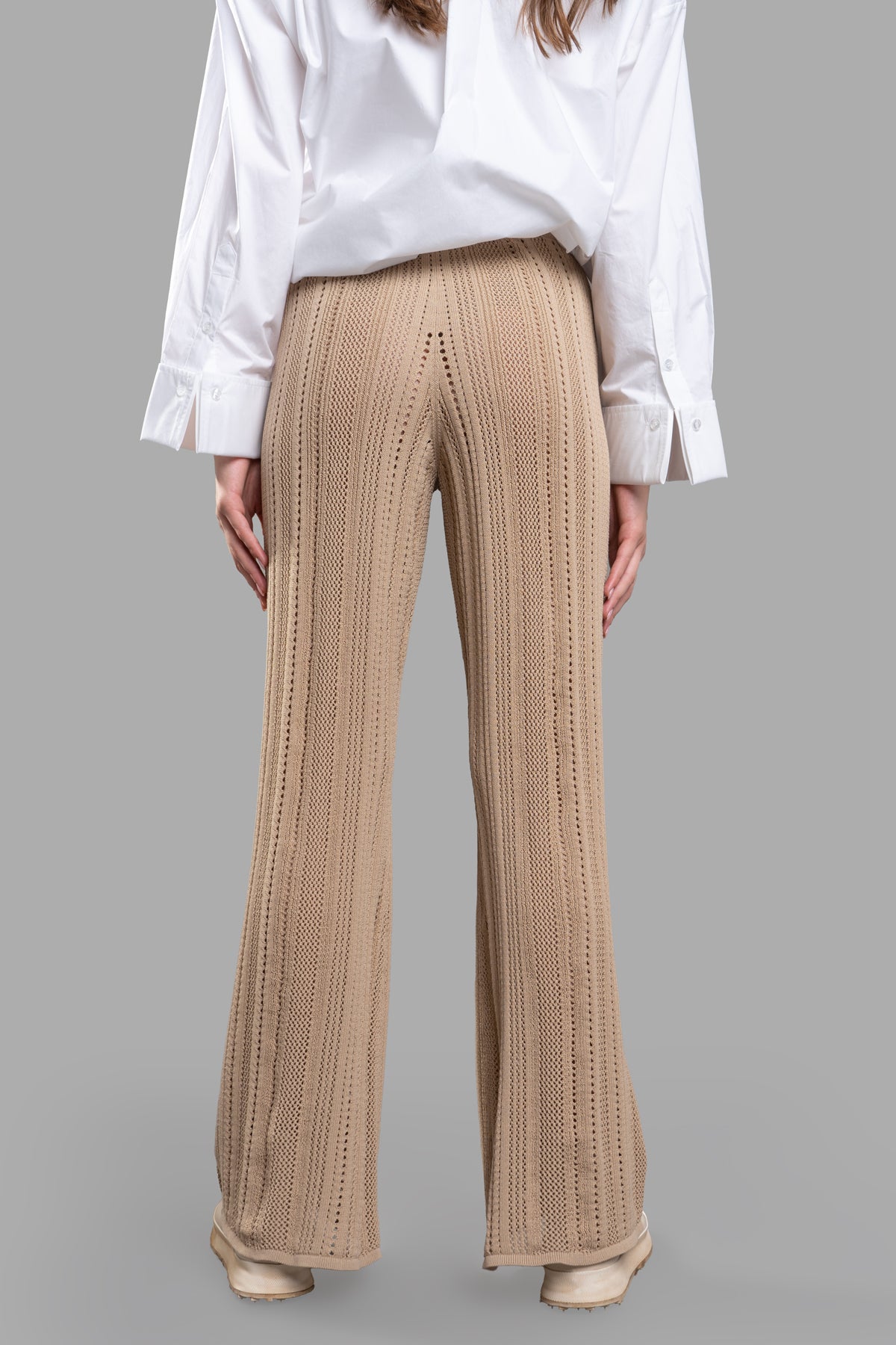 By Malene Birger Knit Trousers shown from the back, featuring a high-waisted, flared design in textured beige knit fabric.