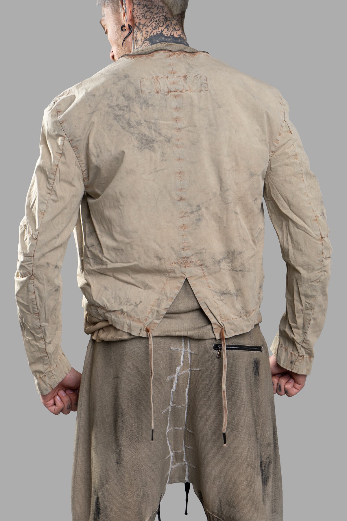Masnada Transformative Linen Parka, beige jacket seen from below, emphasizing its long silhouette and intricate seam.