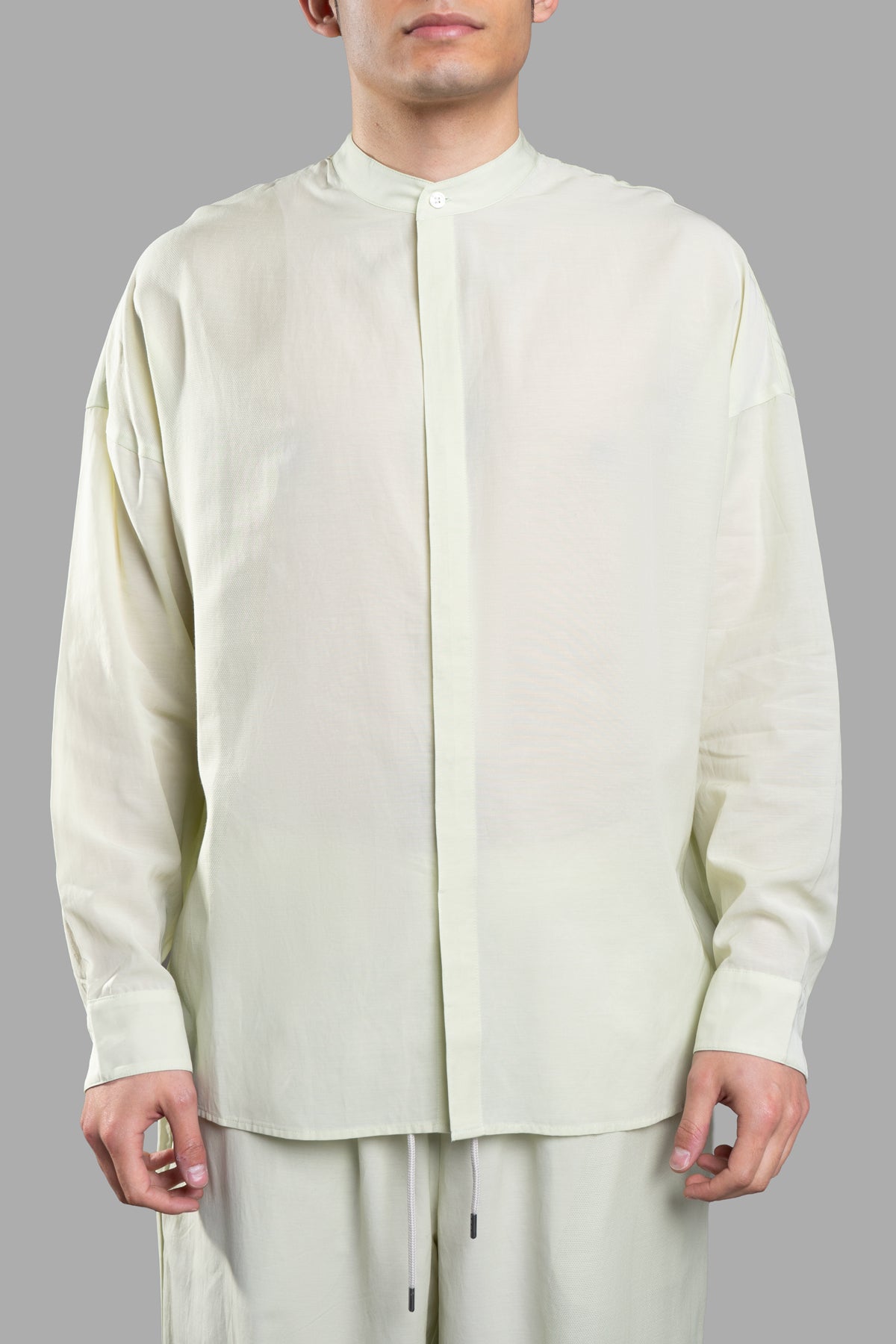 Attachment Collarless Shirt in green, showcasing a long-sleeved design with a stand collar and trendy curved hem.