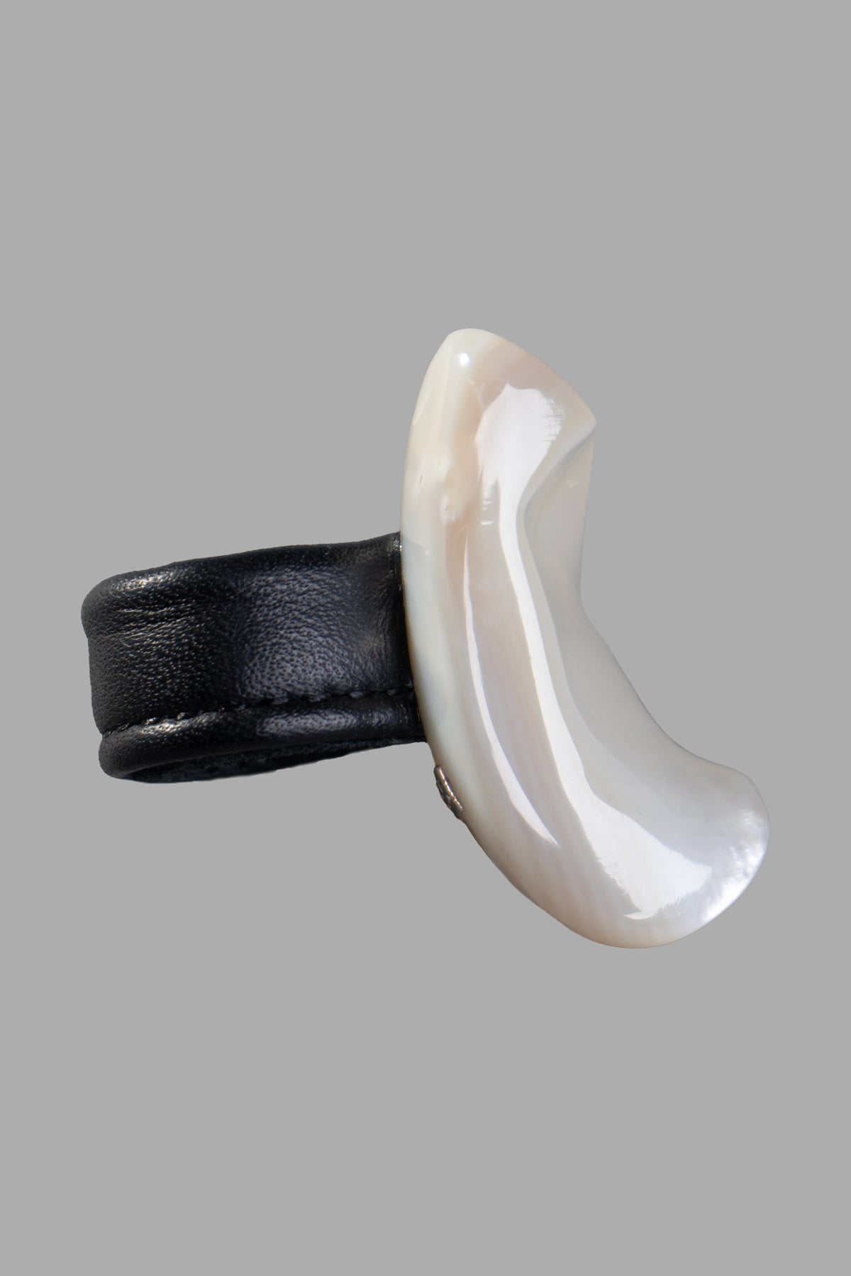 Monies Pearl Statement Ring featuring a large mother of pearl design on a black leather strap, showcasing unique curves and.