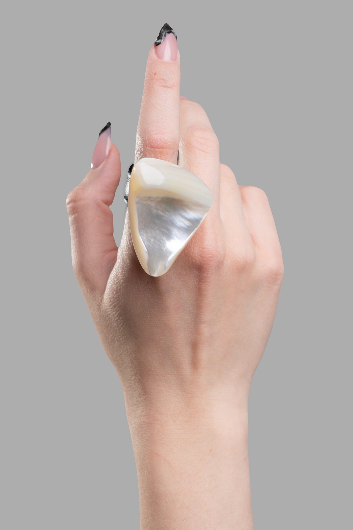 Monies Pearl Statement Ring on model's finger, showcasing a mother of pearl design with a sleek leather strap.