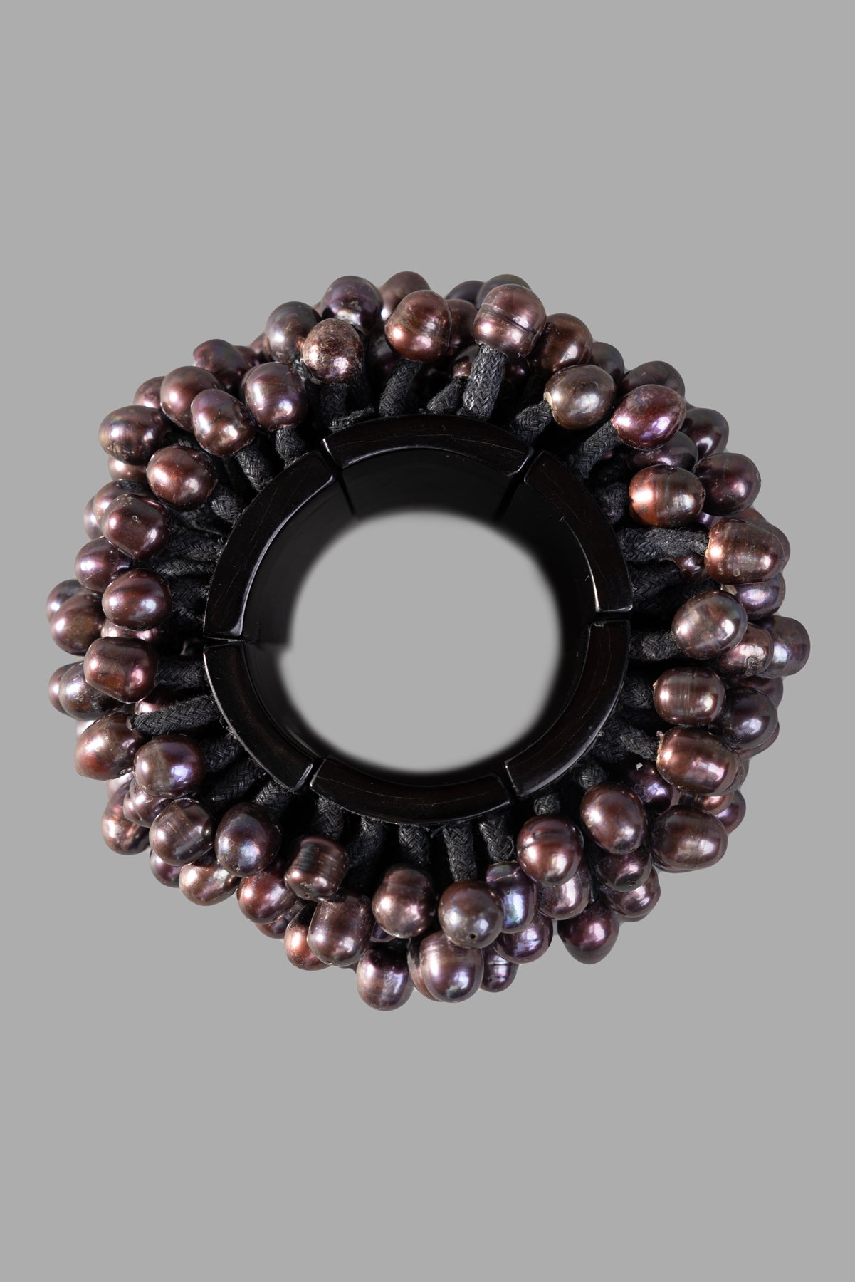 Monies. Statement Bracelet featuring oversized black pearls on ebony wood, viewed from above, showcasing intricate bead.