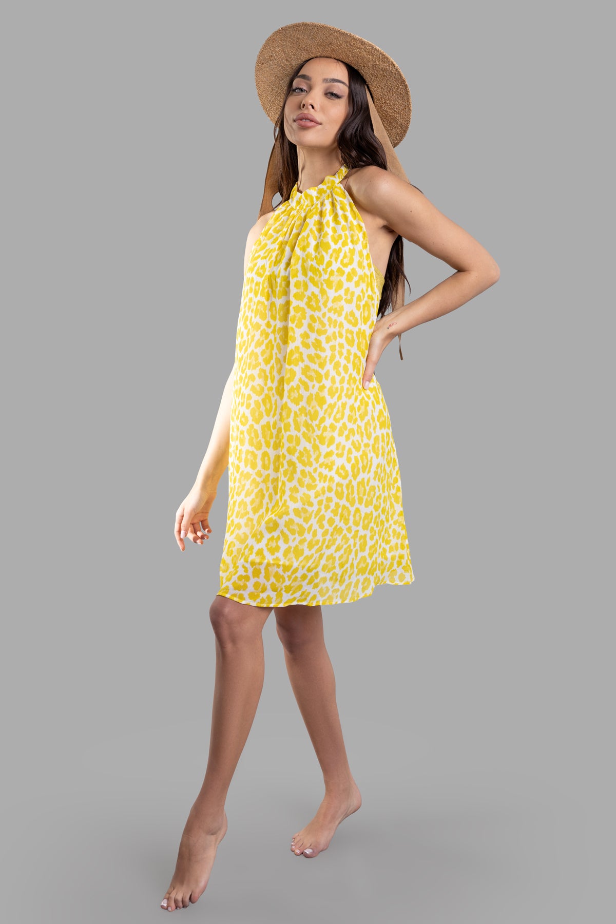 Fisico leopard-print beach dress in yellow, halterneck style, worn by model, showing front view with open back design.