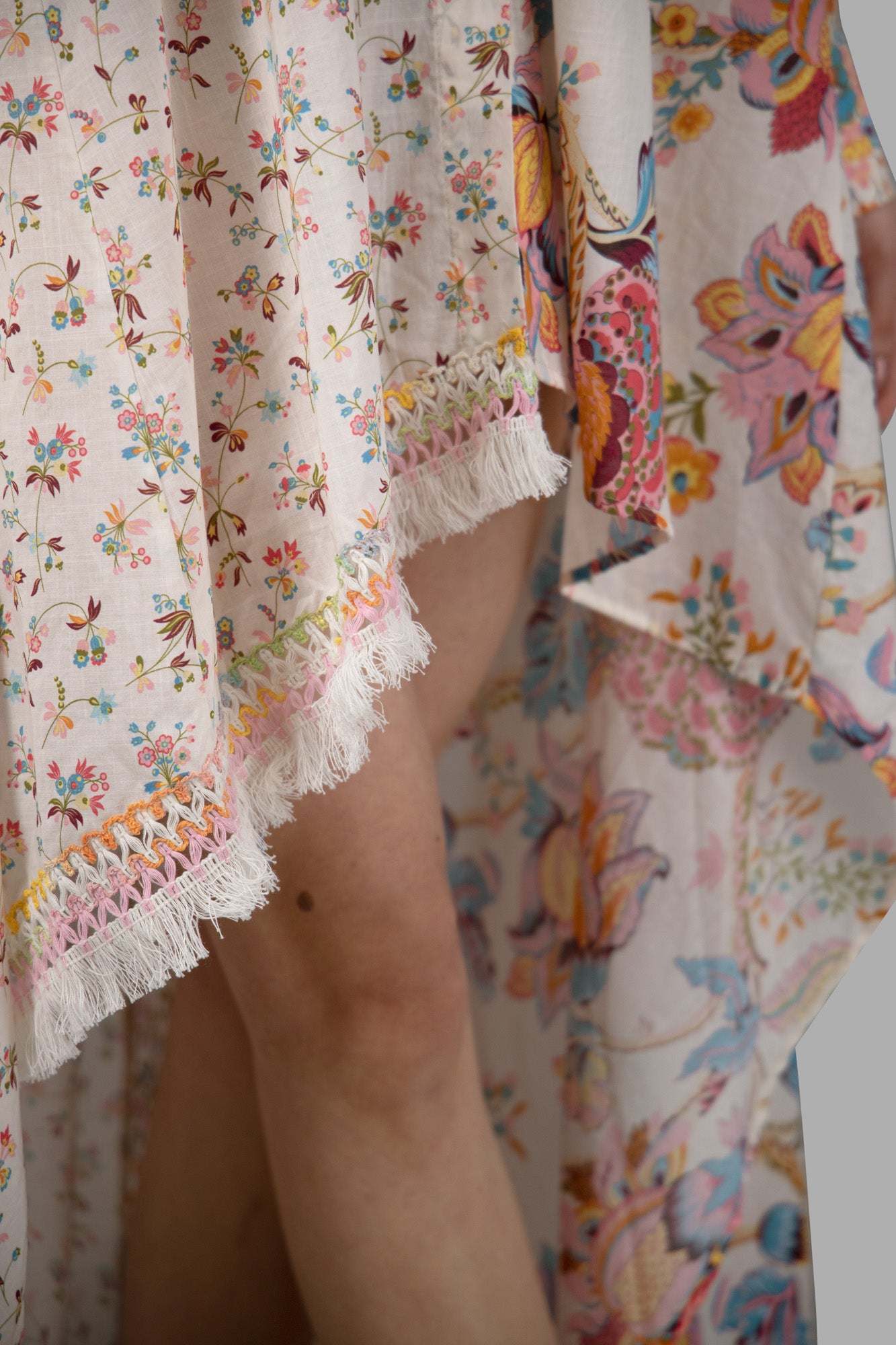 Anjuna Double-Print Asymmetric Dress featuring vibrant floral prints and delicate fringe detailing, shown from the side.