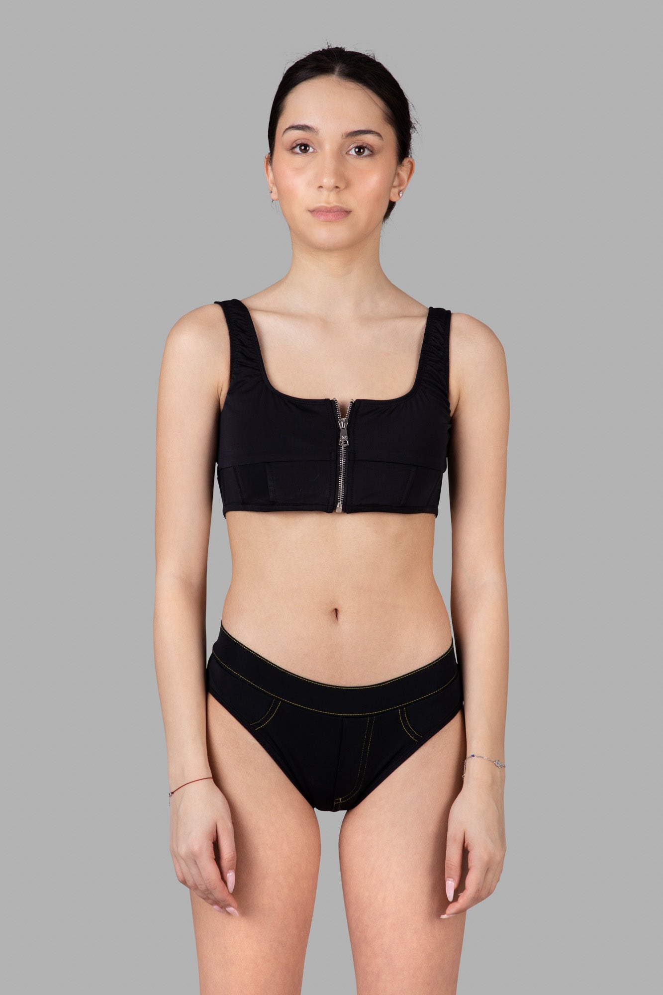 Natasha Zinko Corset-style Bikini Top featuring a black boned bodice and rear zip, modeled for a chic, elegant look.