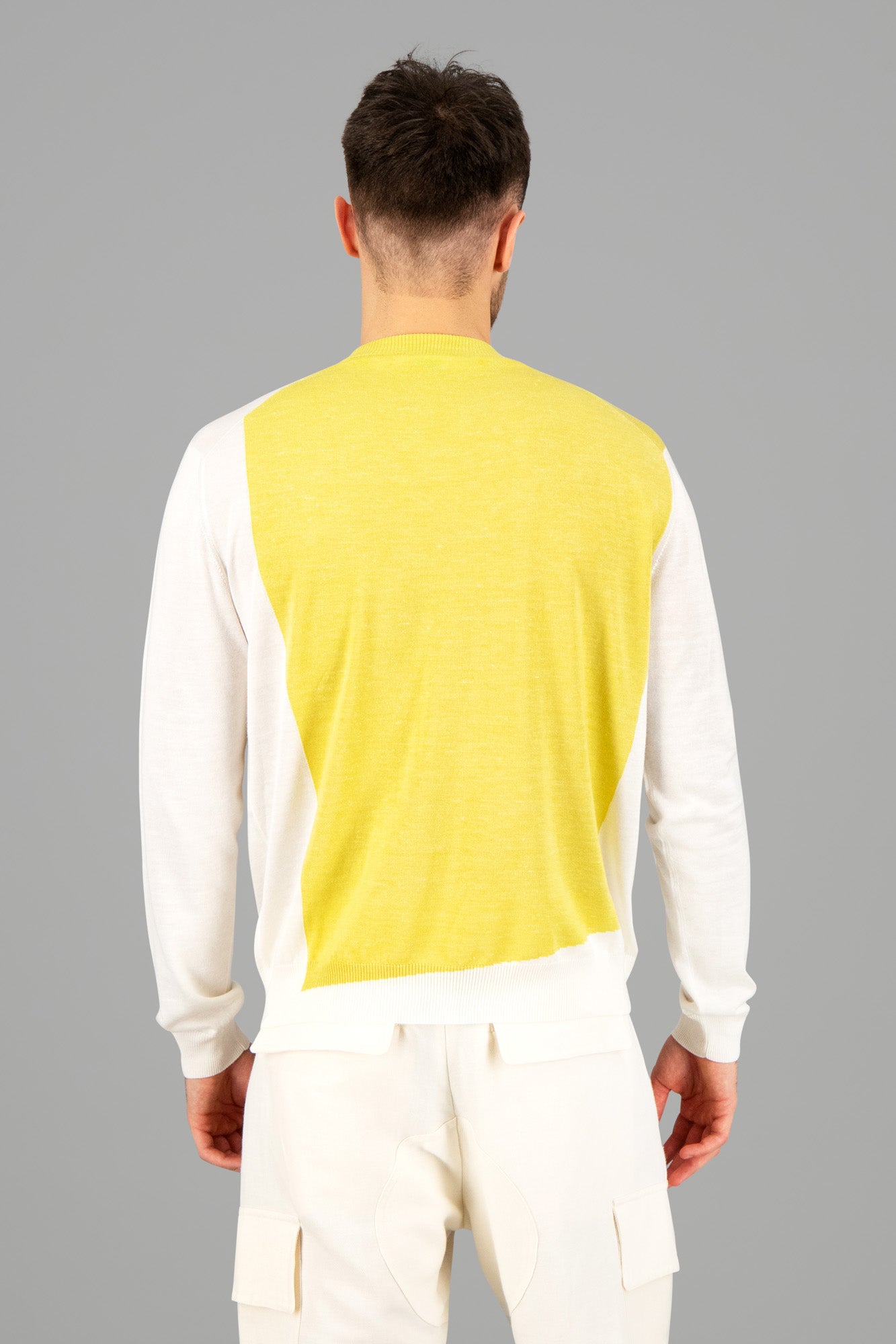 AION. Two-Colored Fine Knit Sweater in yellow and white shown from the back, featuring a color-block design and soft texture.