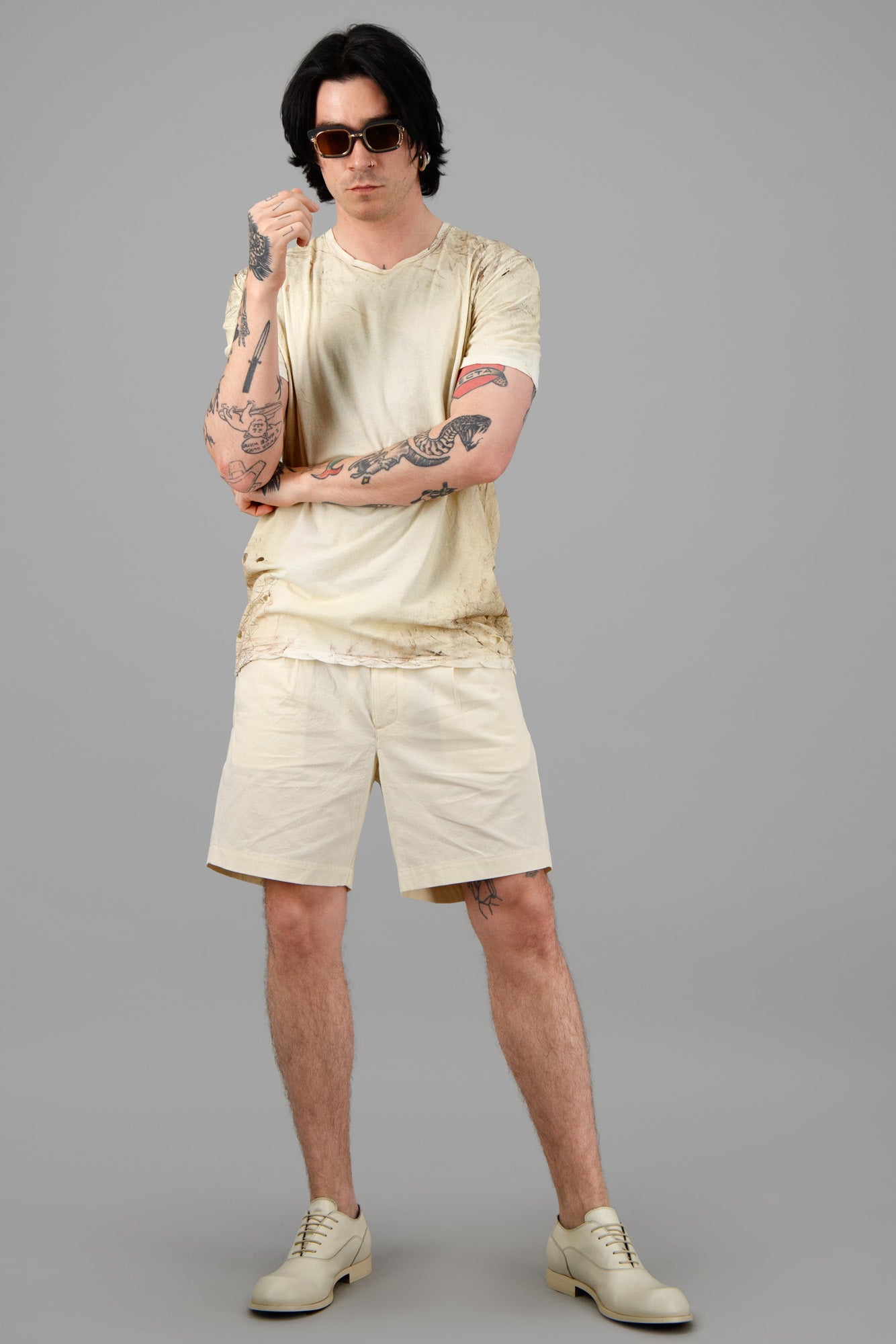 Orlebar Brown sand-colored shorts on model, front view, showcasing cotton fabric and pleated design, ideal for summer.