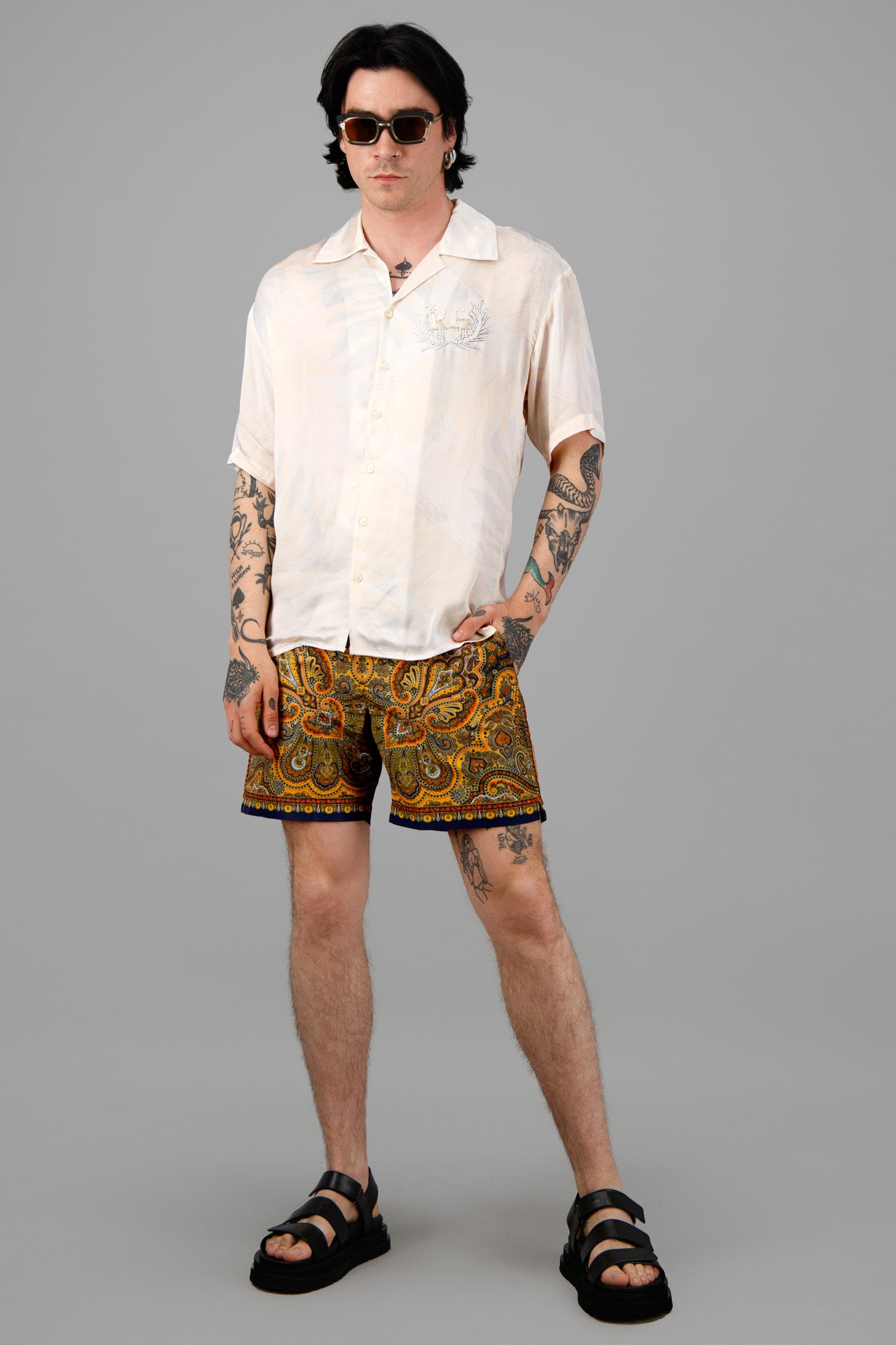 Orlebar Brown Mystique Print Swim Shorts modeled, front view. Features bold paisley pattern, contrasting hem, white sand.