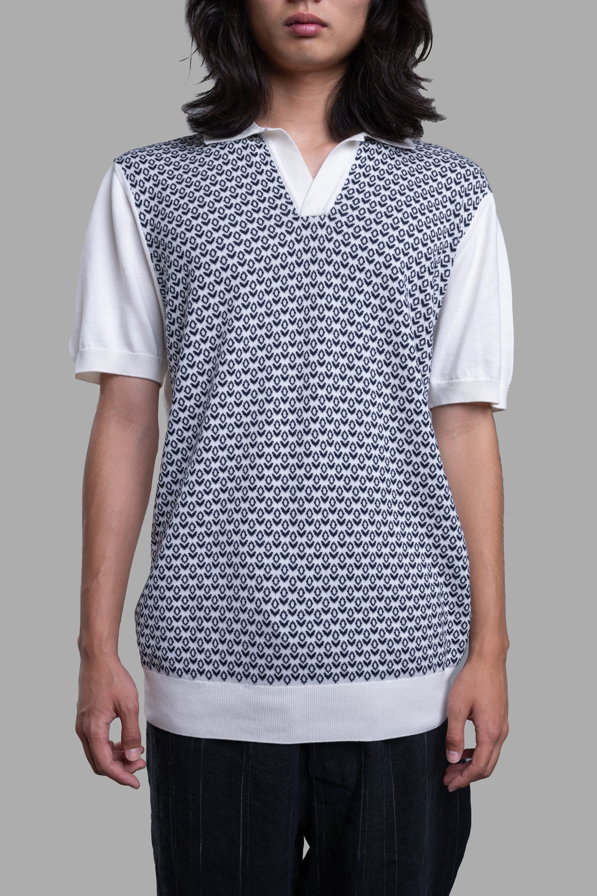 Orlebar Brown Knit Polo Shirt featuring a navy mosaic design, white collar, and ribbed edges, model wearing.