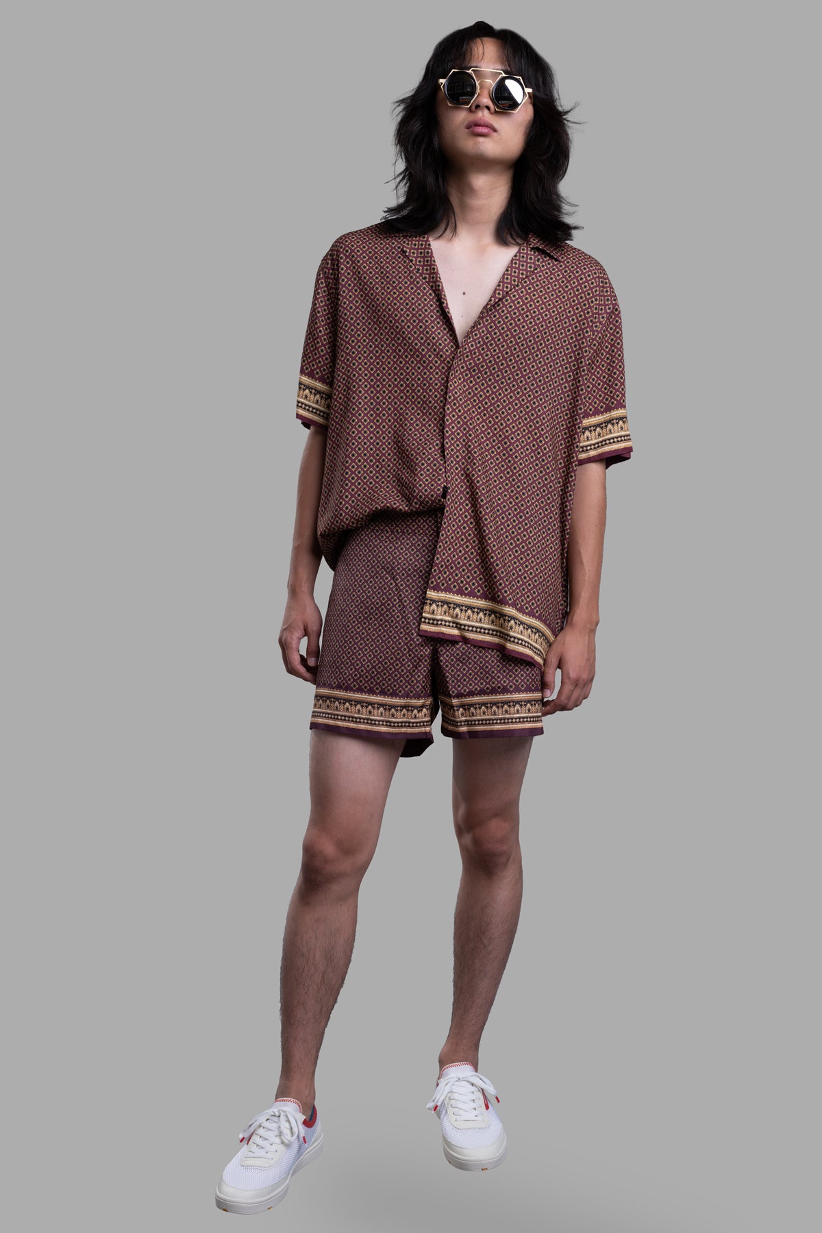Orlebar Brown Copper Swim Shorts on model, showcasing floral geometric pattern with paisley border, retro style.