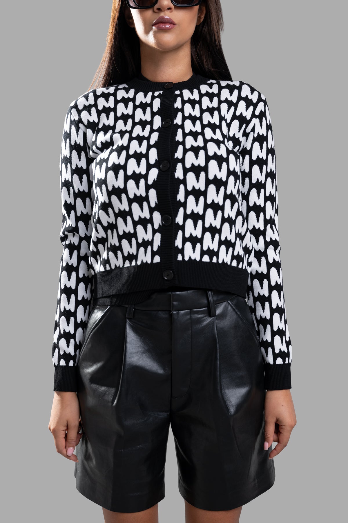 MSGM Jacquard Cardigan in black and white featuring iconic M pattern, crew neckline, and front buttons, styled with shorts.