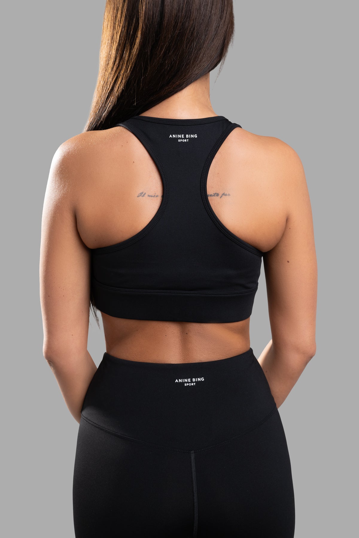 Anine Bing Blaire Sports Bra showcased from the back, highlighting its sleek design and logo detail on model.