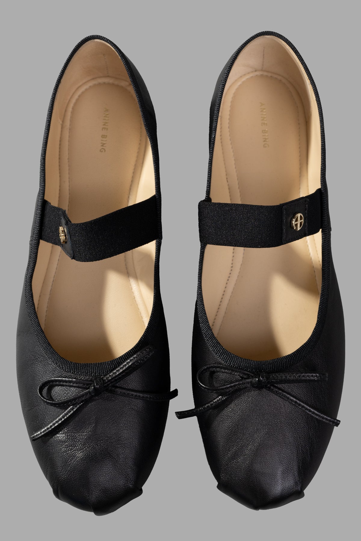 Anine Bing Ballet Flats in black, featuring a soft leather design with elastic strap and bow detail, top view.