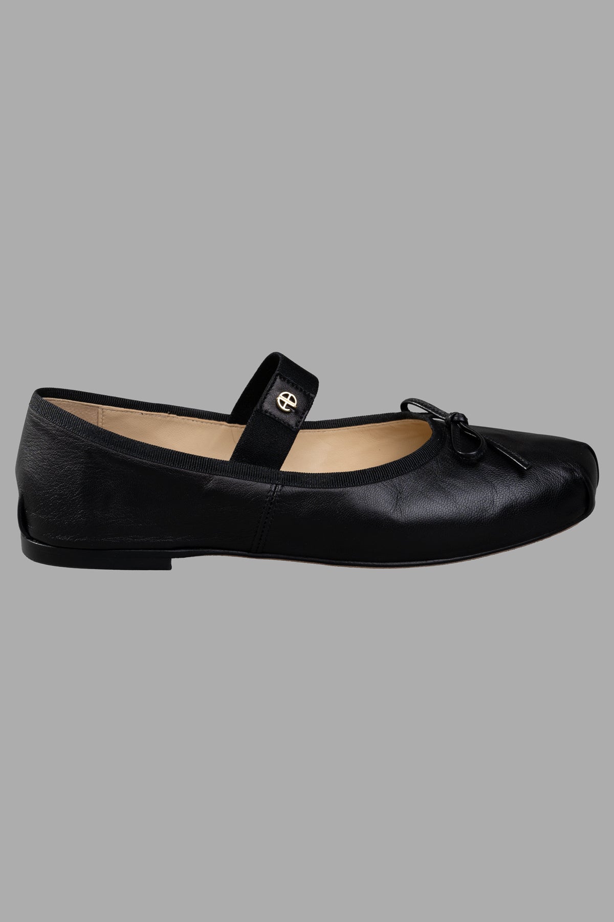 Anine Bing Ballet Flats, side view of black leather shoe with strap and bow detail.
