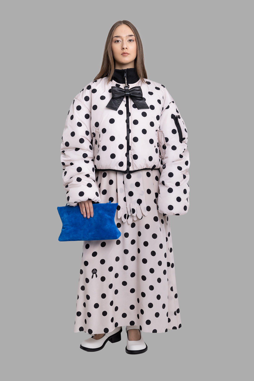 Natasha Zinko women's beige polka dot bomber jacket on model full length with matching maxi skirt and blue clutch.