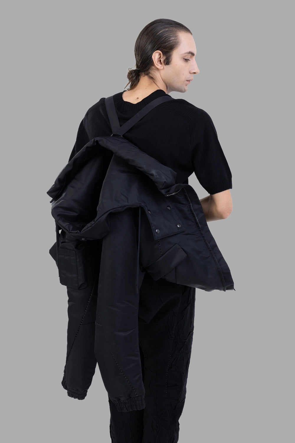 Masnada bomber jacket in black, 3/4 rear view, internal harness straps worn over shoulders