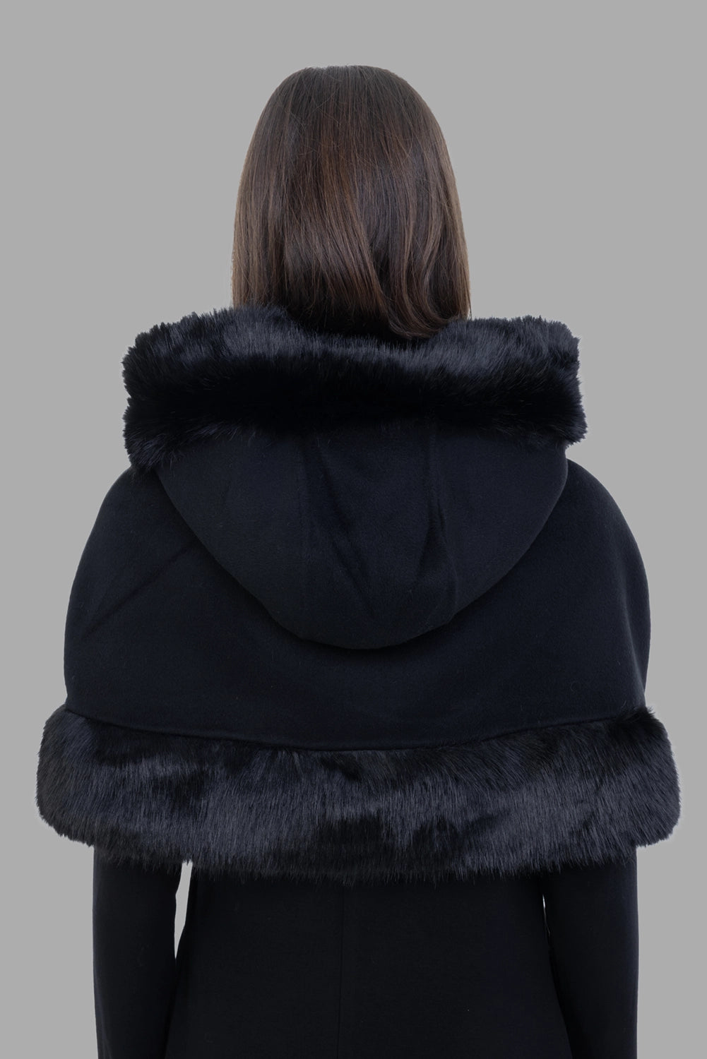 By Malene Birger women cape in black, back view, hood folded down showing faux-fur band.