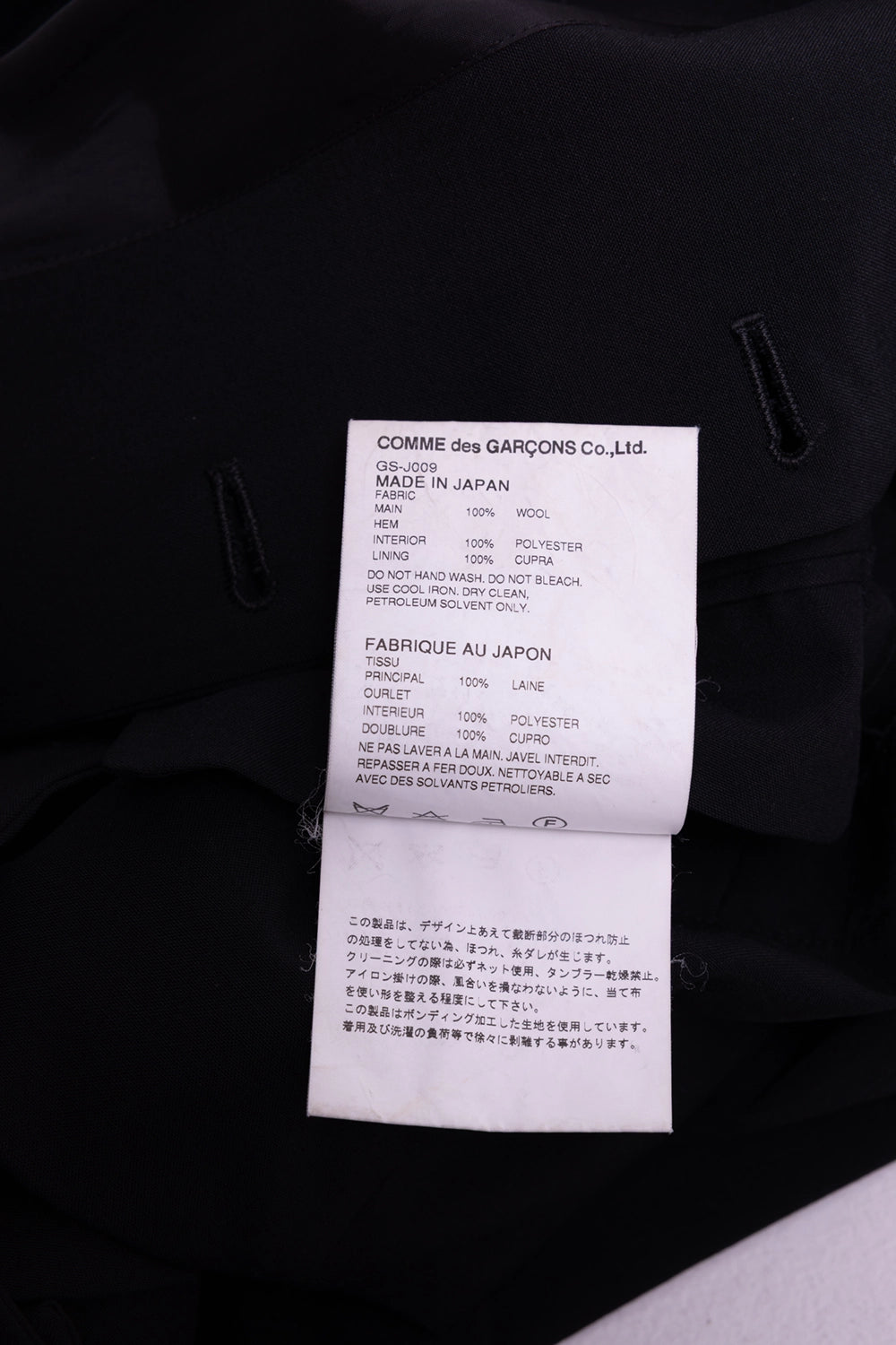 Pre-owned Comme des Garçons coat in black, care tag view, fabric content label and made in Japan text