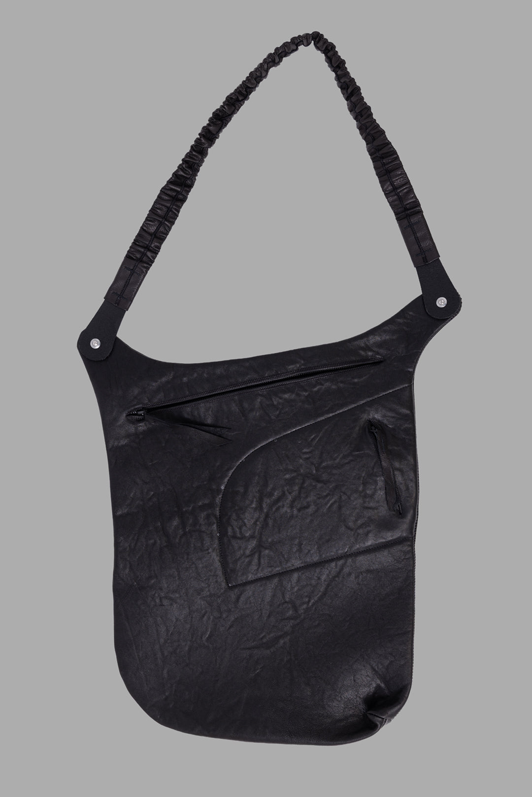 Isaac Sellam Experience unisex black leather crossbody bag, back view with zip pockets and curved seam panel.