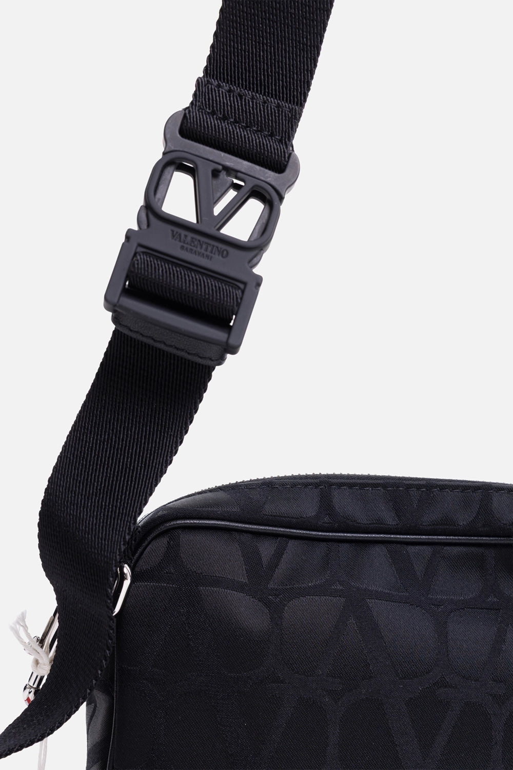 Pre-owned Valentino Garavani men’s crossbody bag in black, strap buckle close-up, matte V-logo hardware