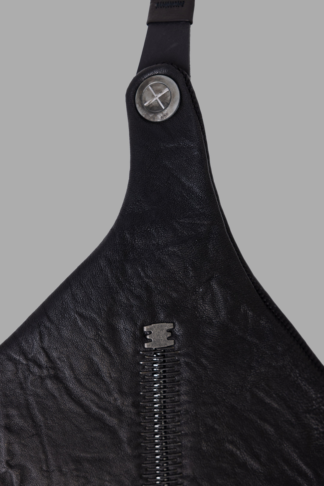 Isaac Sellam Experience unisex black leather crossbody bag, hardware close-up of screw studs and metal spine zipper.