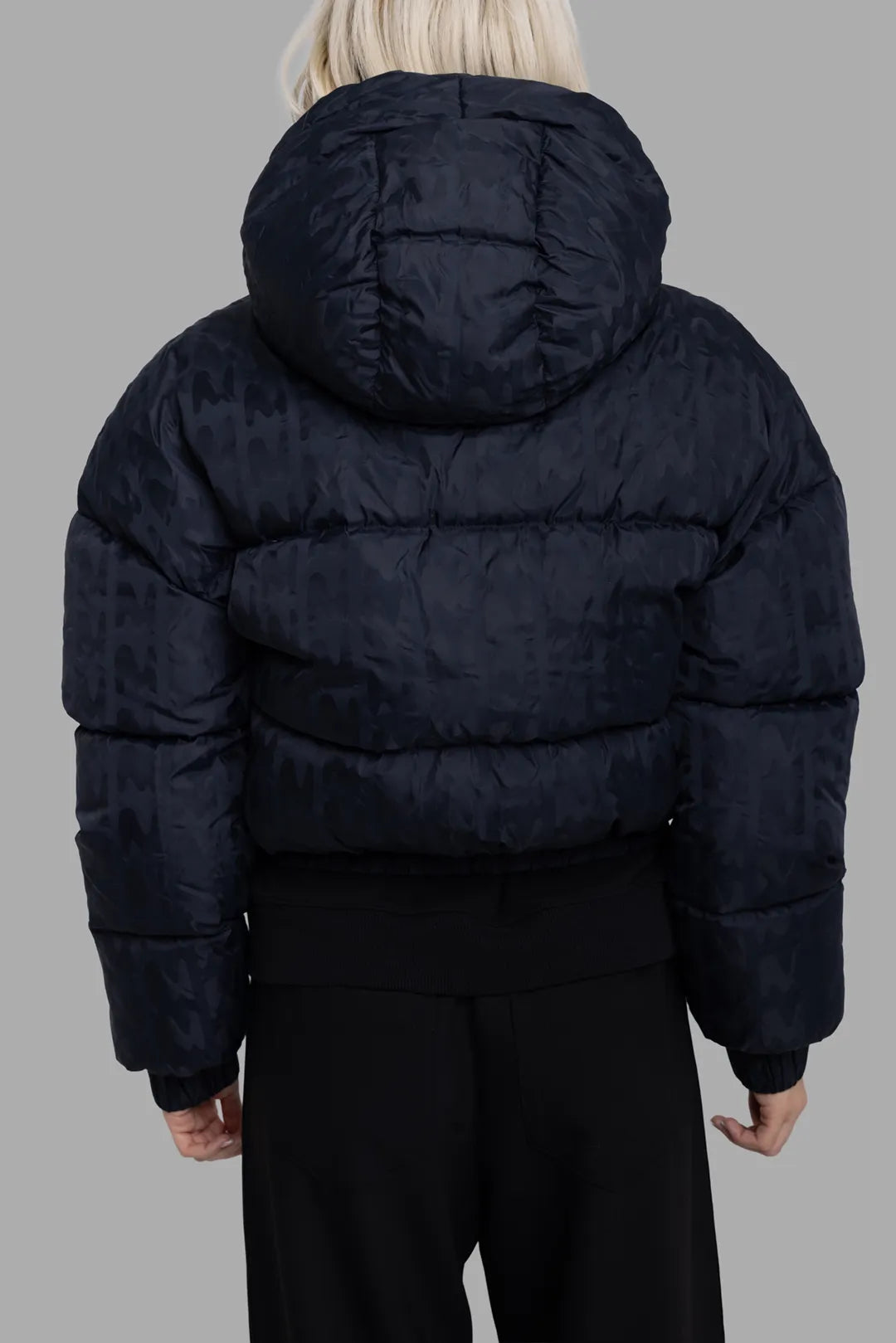 MSGM women's black logo-jacquard down jacket, back view with hood up, quilted panels and elastic hem.